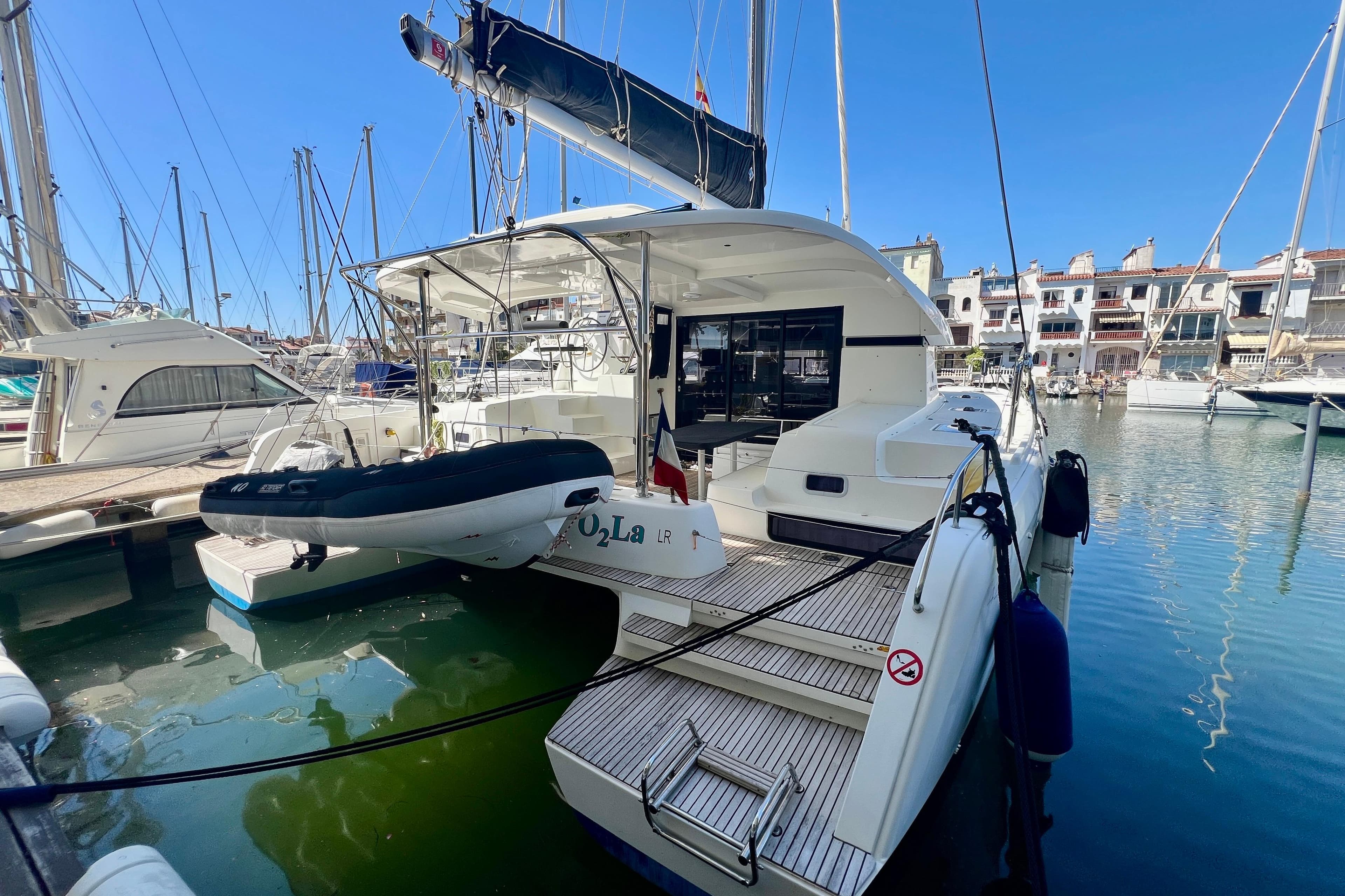 2019 Lagoon 42 catamaran docked in a marina under clear blue skies.