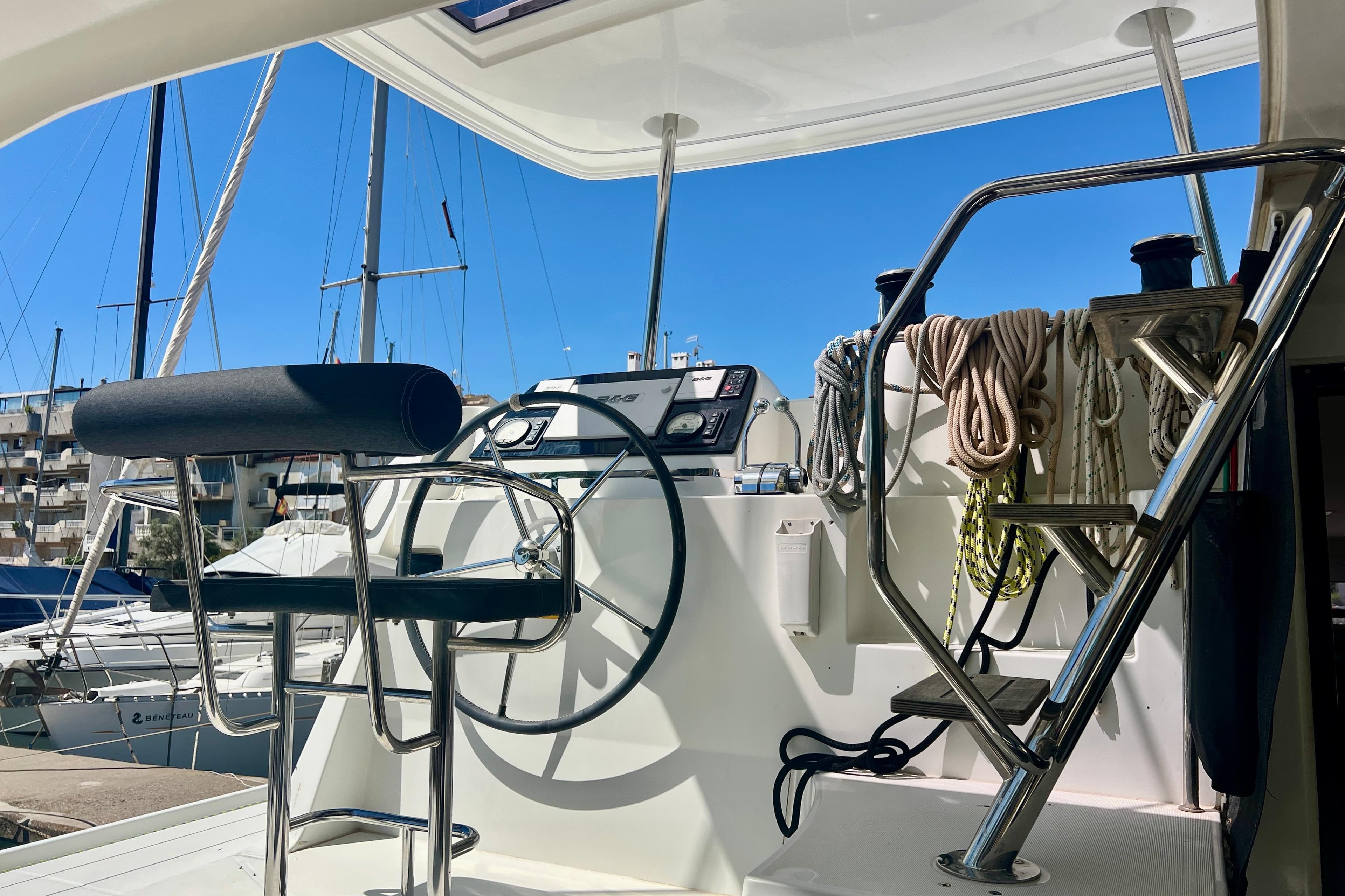 Helm station of 2019 Lagoon 42 catamaran with steering wheel and ropes, docked at marina.