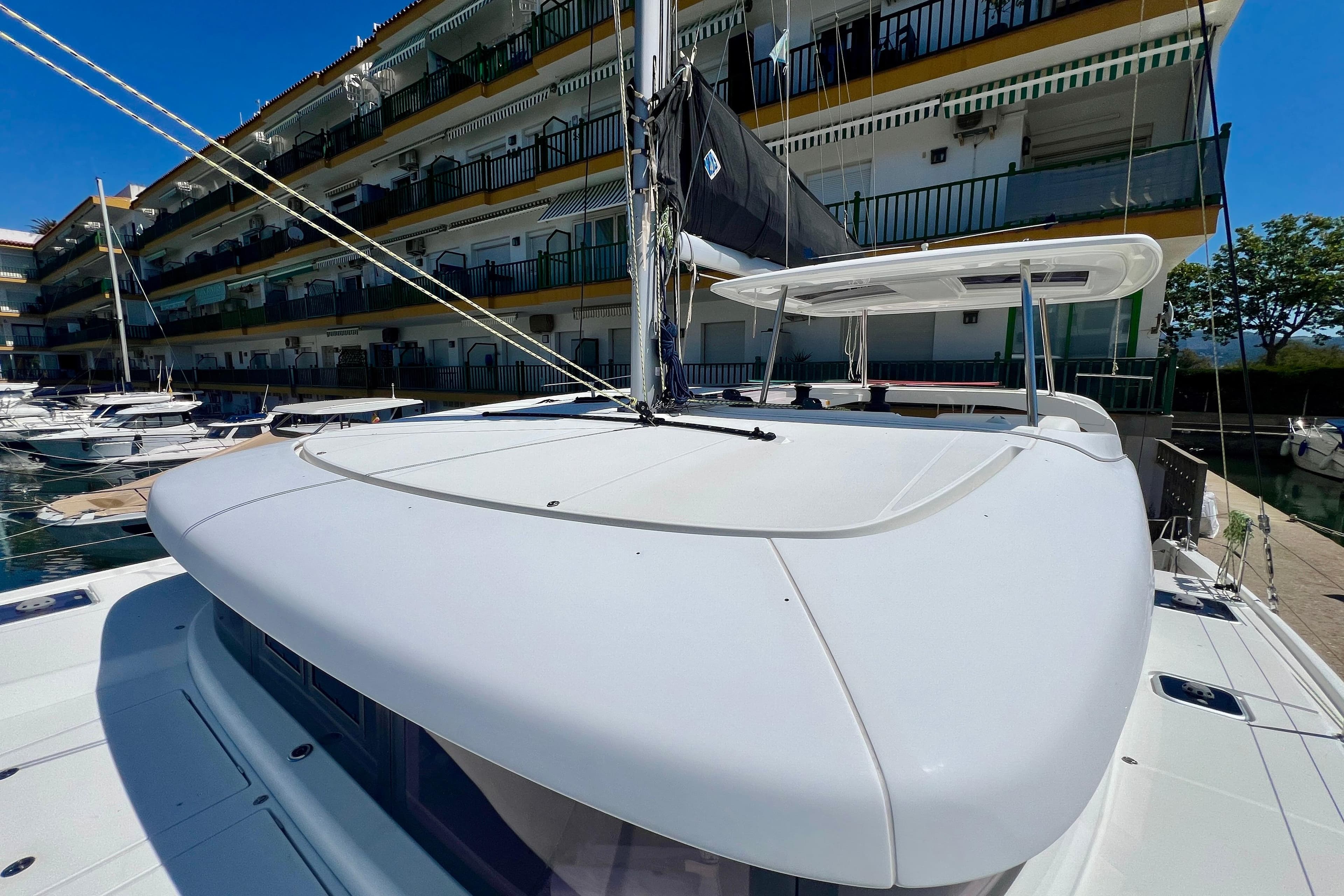 2019 Lagoon 42 catamaran docked near waterfront apartments, showcasing sleek design and spacious deck.