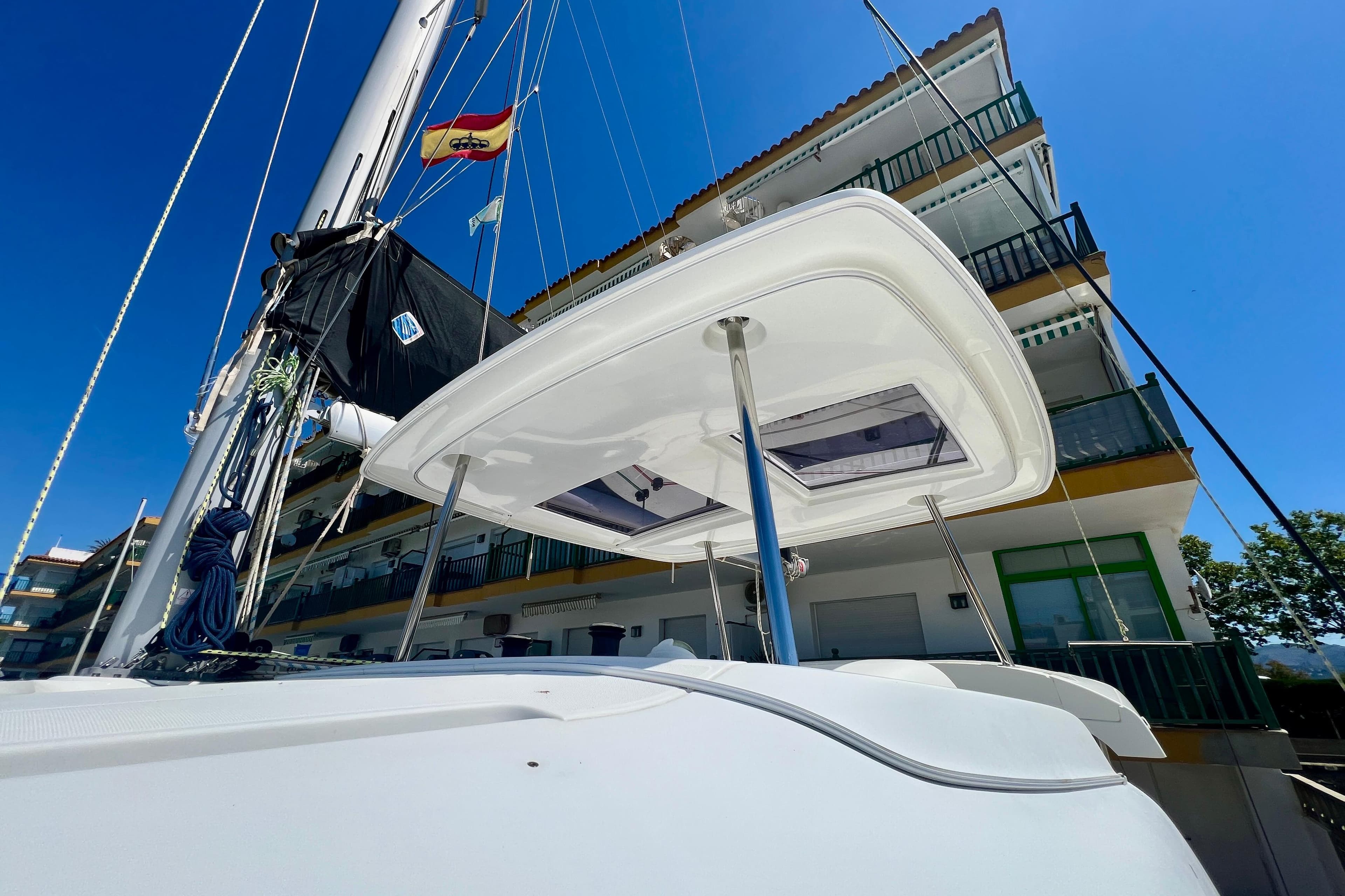 2019 Lagoon 42 catamaran docked near a building under a clear blue sky.