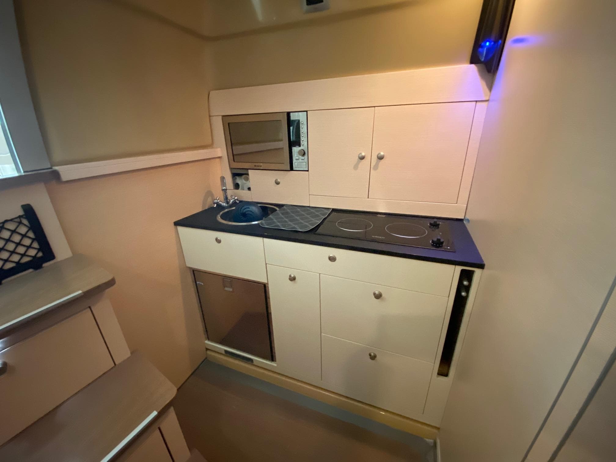 Compact kitchen in 2012 Cranchi M38 yacht with stove, sink, and microwave.