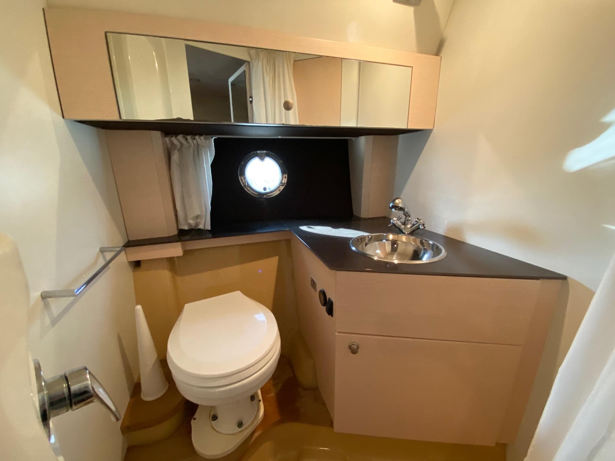 Cranchi M38 2012 yacht bathroom with toilet, sink, mirror, and porthole window.