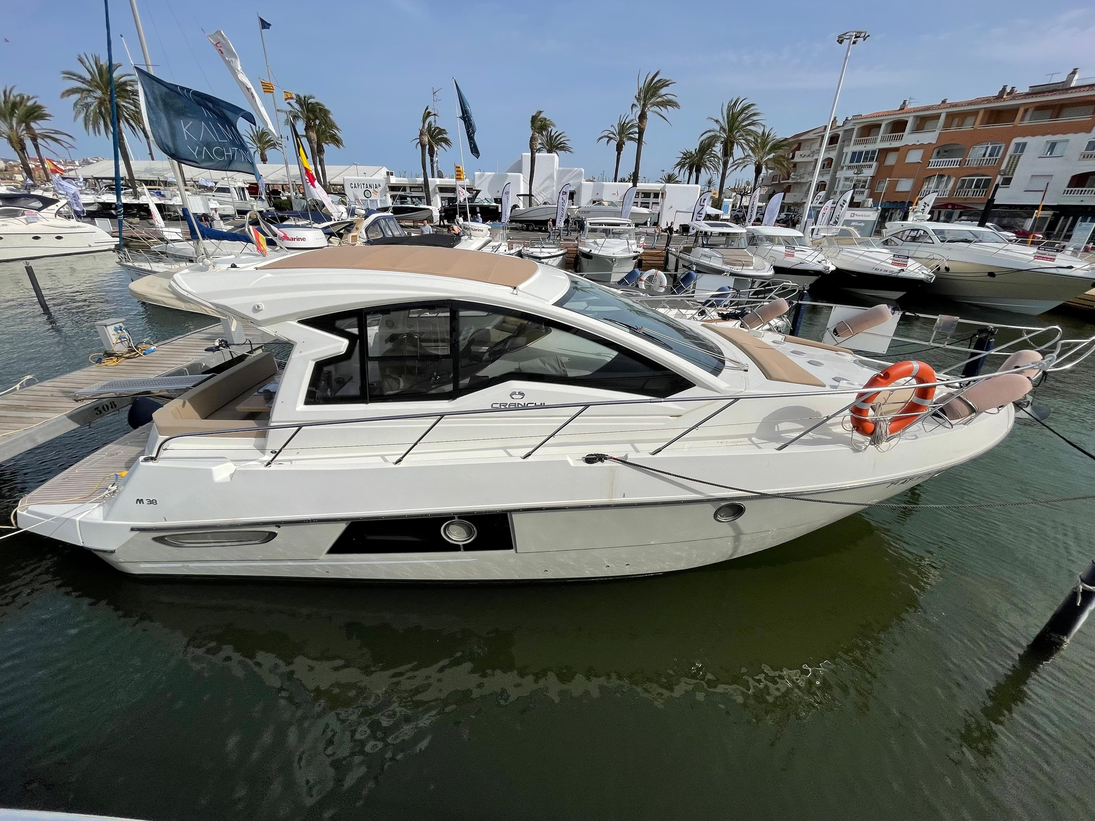 2012 Cranchi M38 yacht docked in a marina with palm trees and buildings.