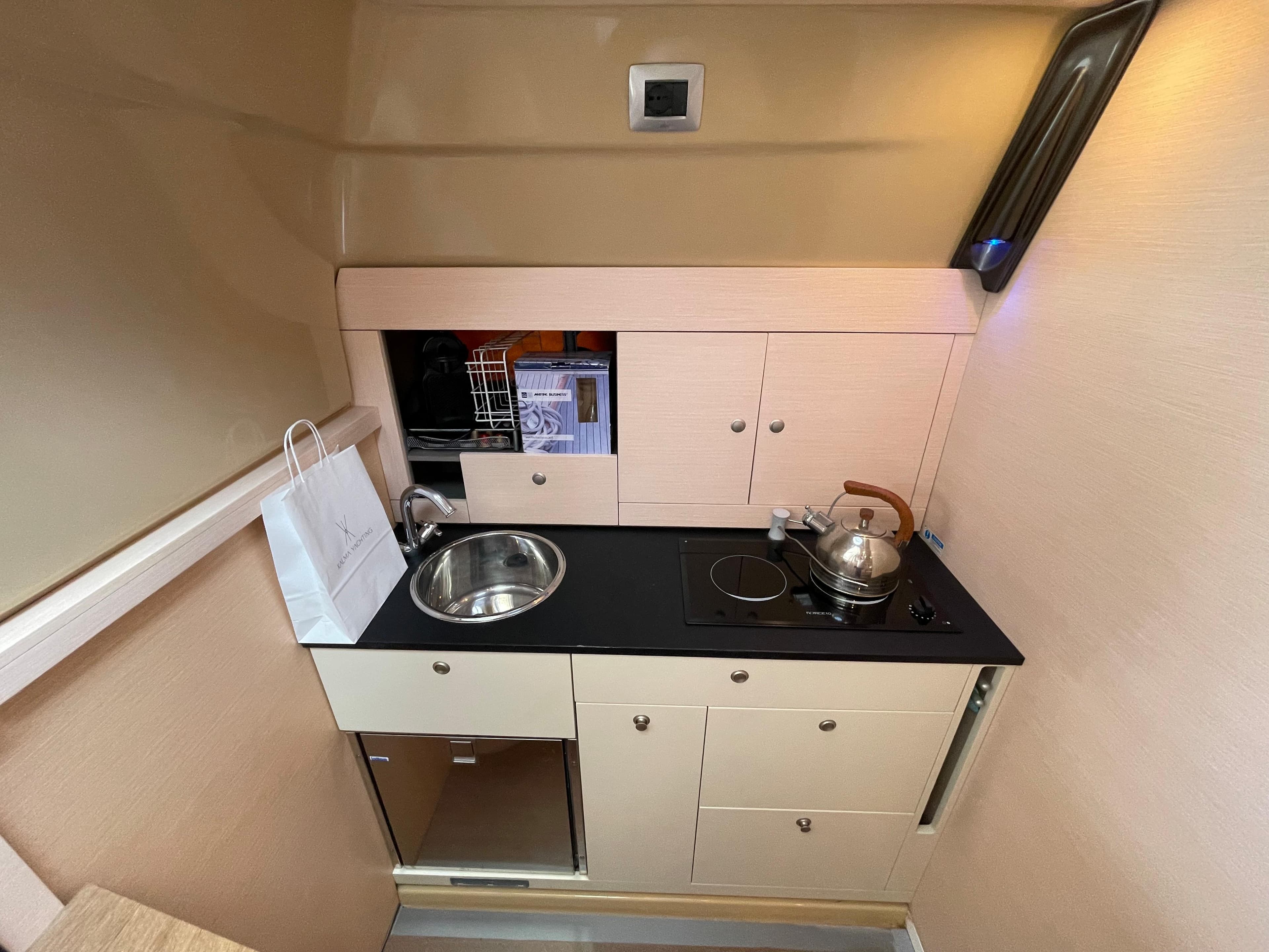 Compact kitchen in 2012 Cranchi M38 yacht with sink, stove, and storage cabinets.