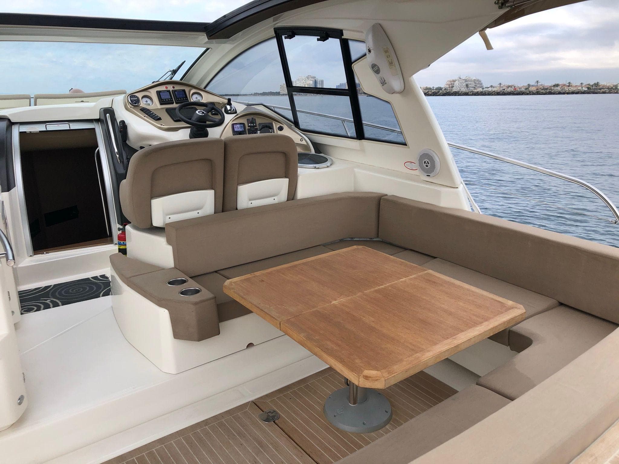 2012 Cranchi M38 yacht interior with seating and wooden table, overlooking calm waters.