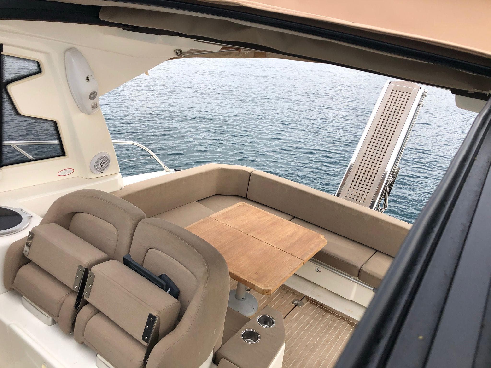 2012 Cranchi M38 yacht interior with beige seating and wooden table, overlooking the sea.