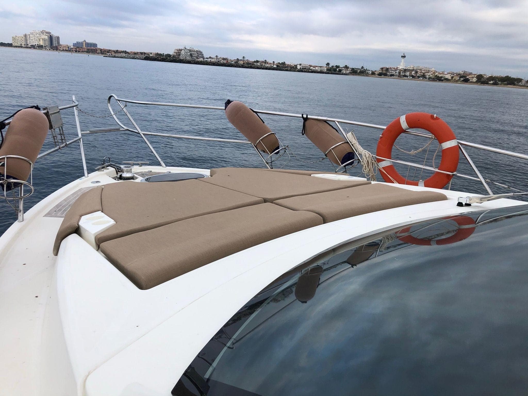 2012 Cranchi M38 yacht with sunbathing deck, life ring, and scenic coastal view.
