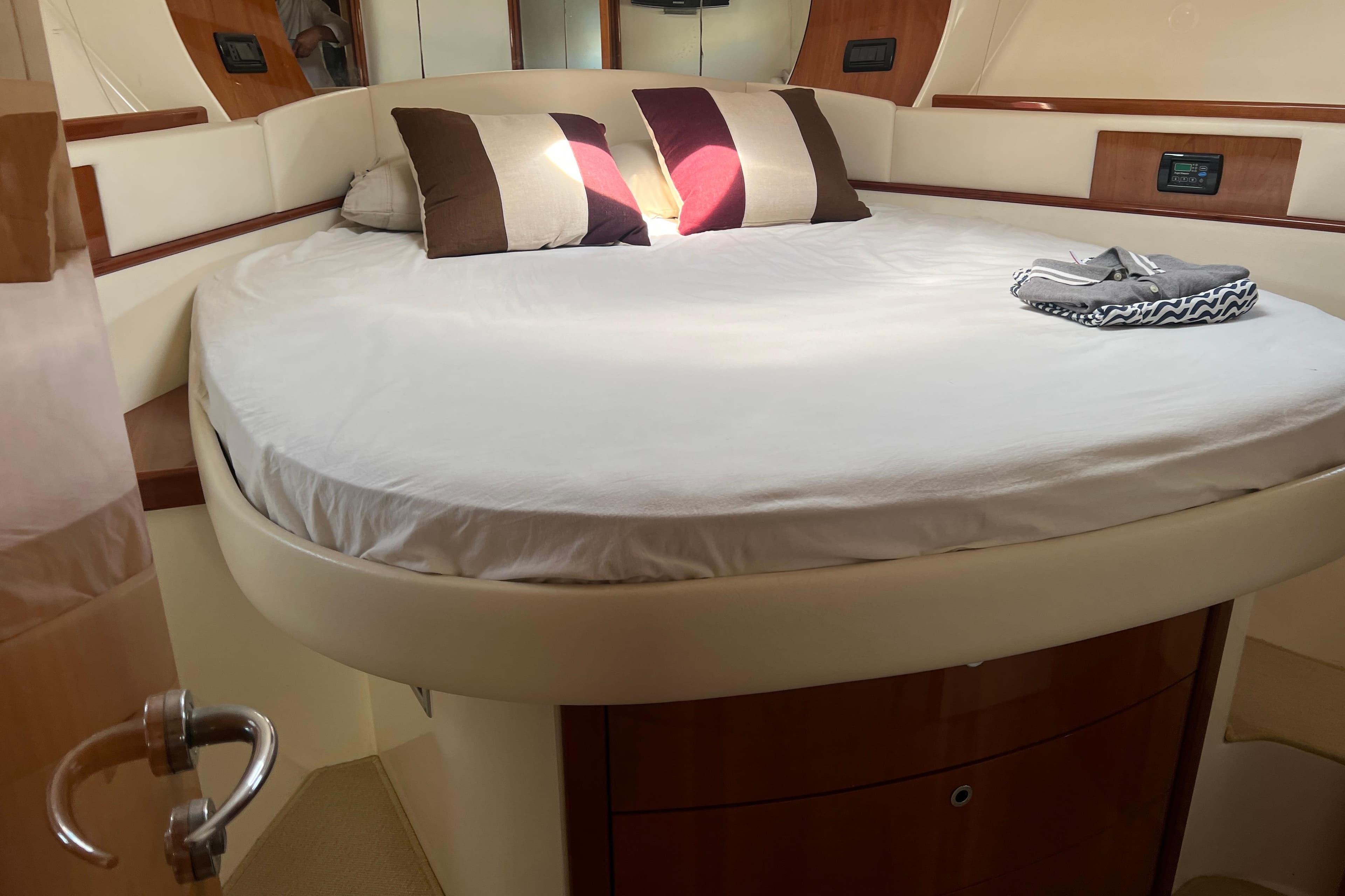 Luxurious bedroom interior of 2007 Pershing 50 yacht with round bed and pillows.
