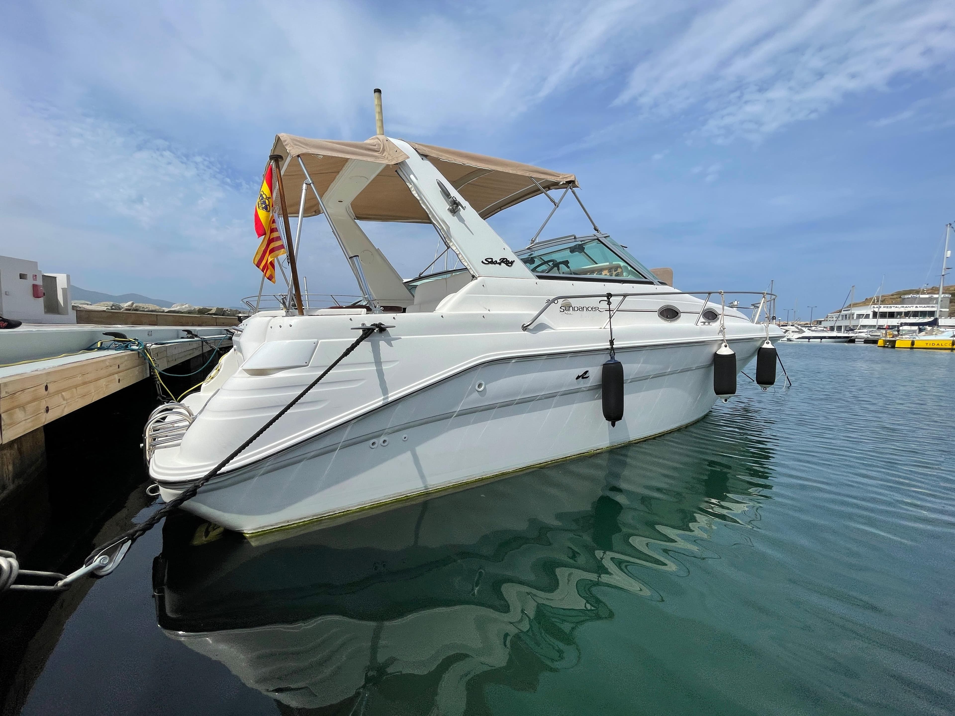 A white 1997 Sea Ray 290 Sundancer docked in a marina, featuring a beige canopy.