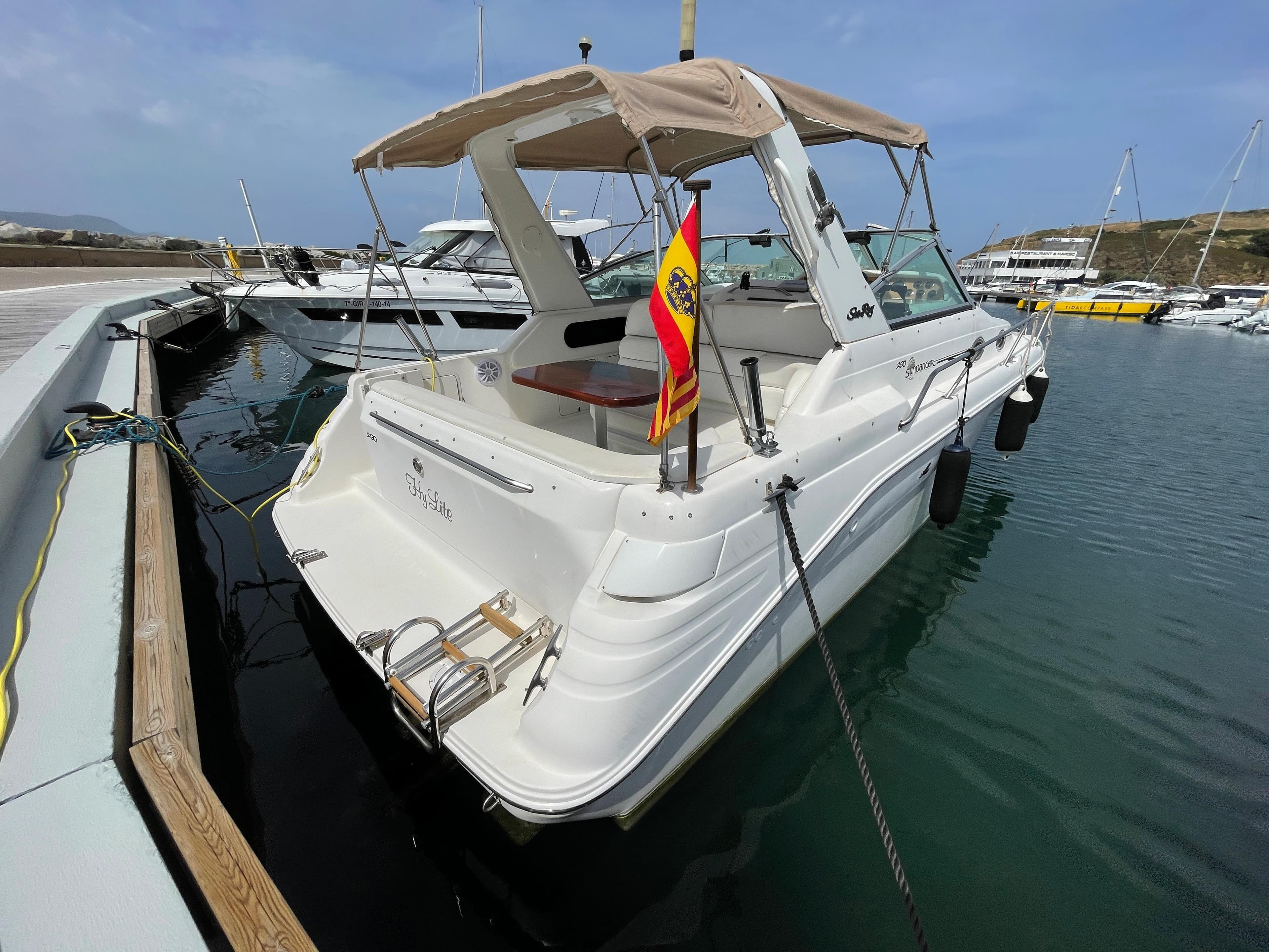 A 1997 Sea Ray 290 Sundancer docked in the water, featuring a beige canopy.