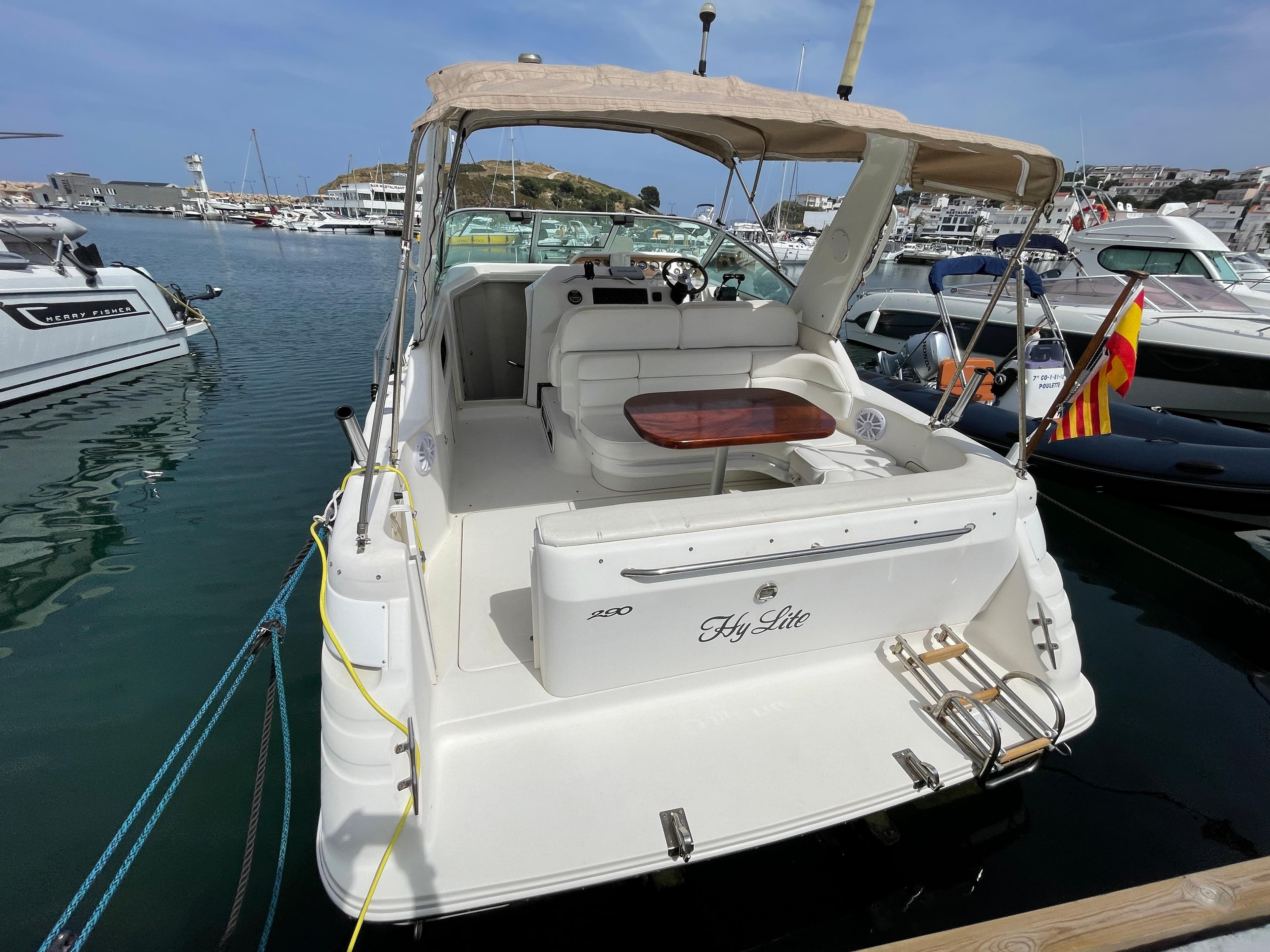 A 1997 Sea Ray 290 Sundancer docked in a marina. It features an open cockpit with a wooden table.