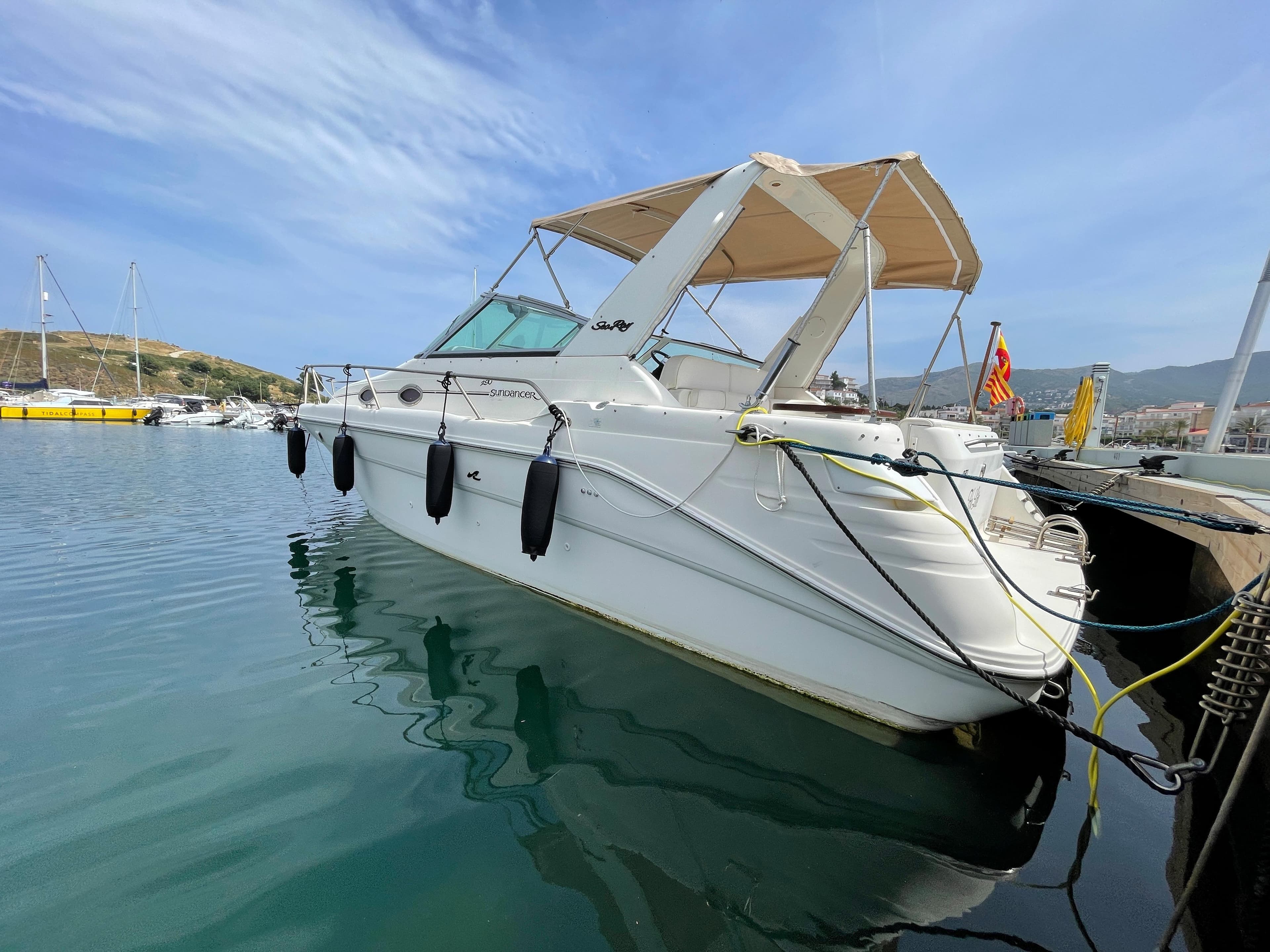 A 1997 Sea Ray 290 Sundancer in the water, featuring a beige canopy and fenders.