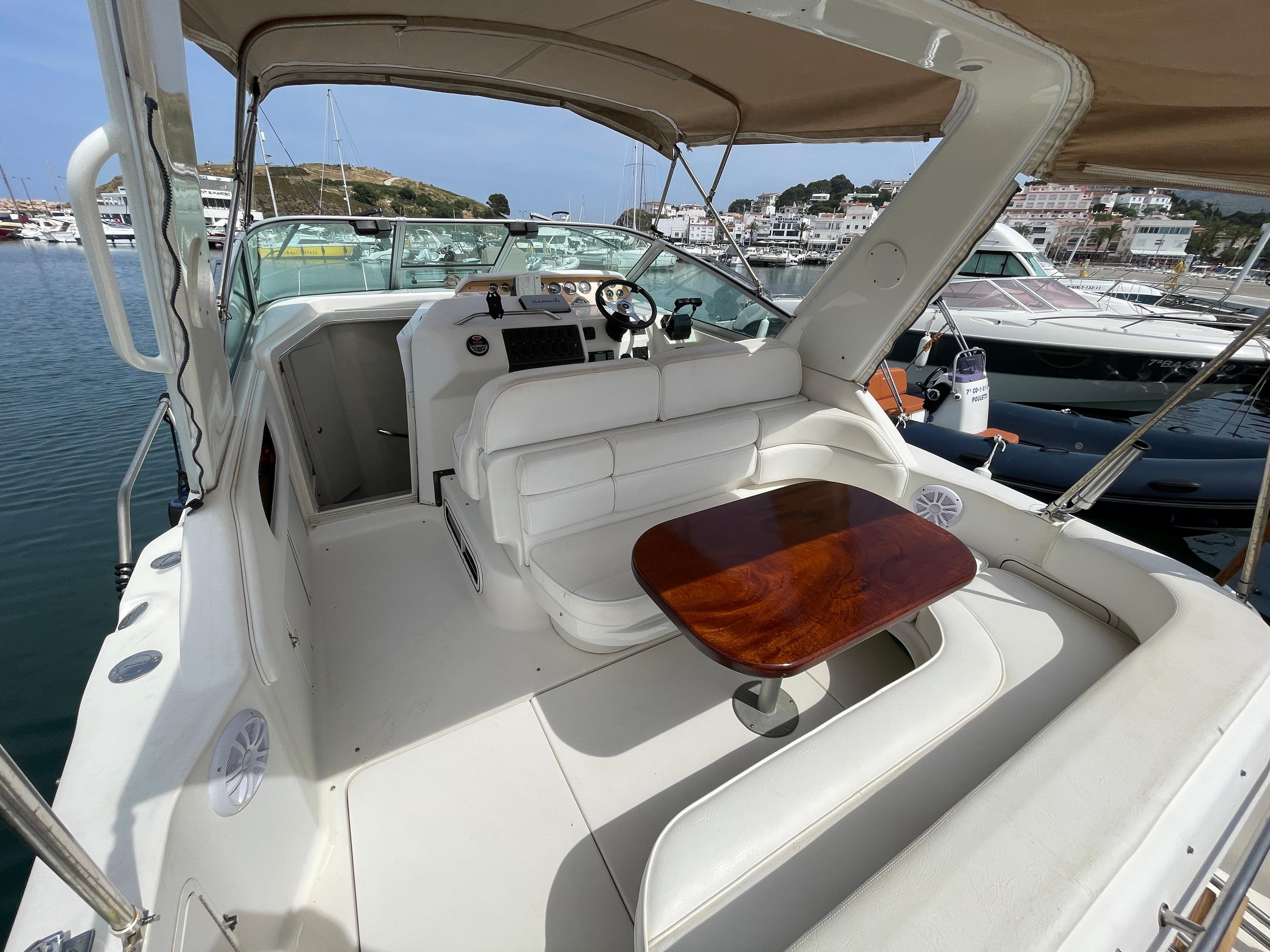 The image shows the cockpit of a 1997 Sea Ray 290 Sundancer with a wooden table and white seating.