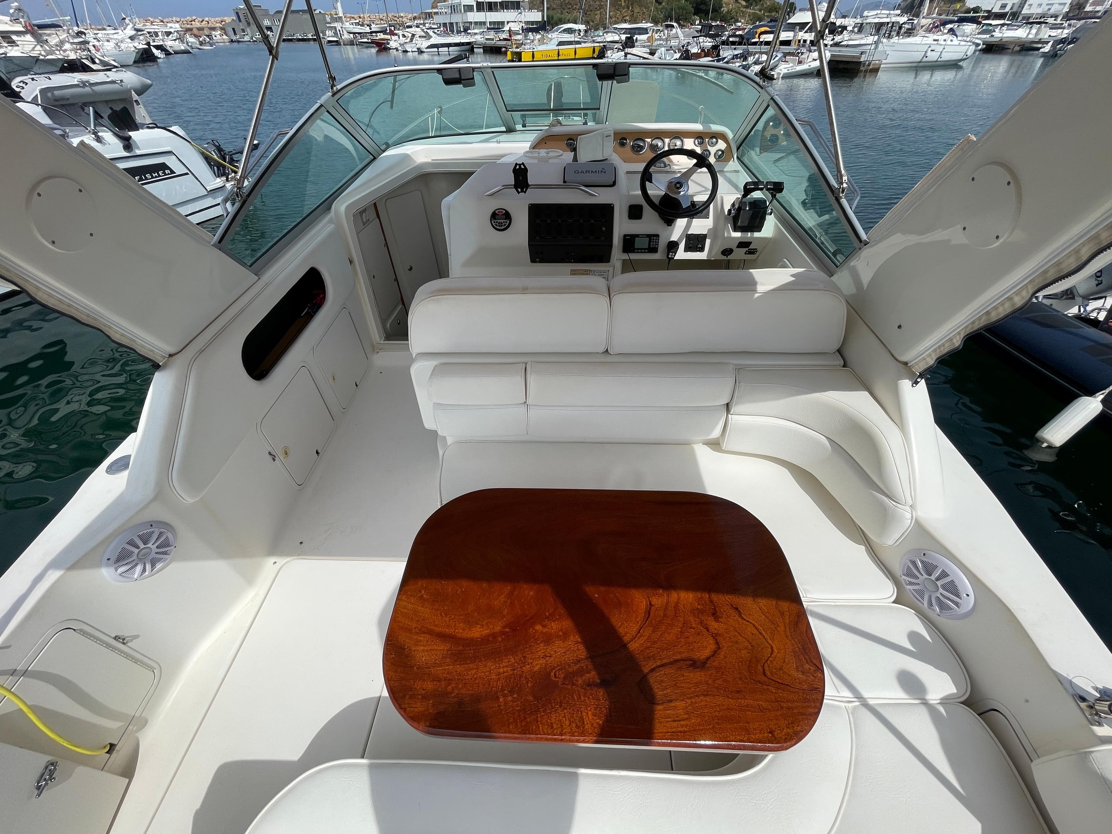 The image shows the cockpit of a 1997 Sea Ray 290 Sundancer with white upholstery and a wooden table.