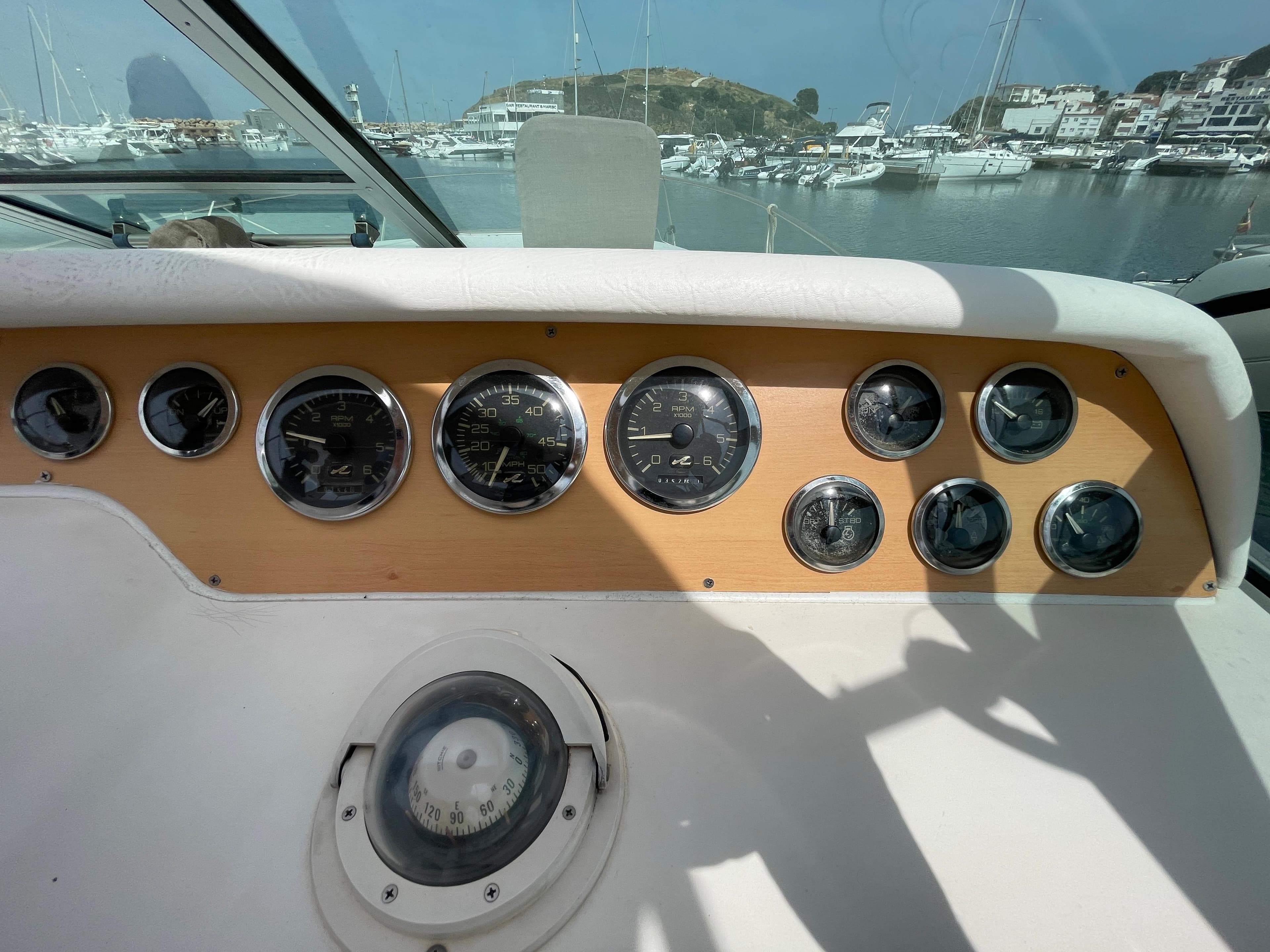 The dashboard of a 1997 Sea Ray 290 Sundancer with multiple gauges and a compass.