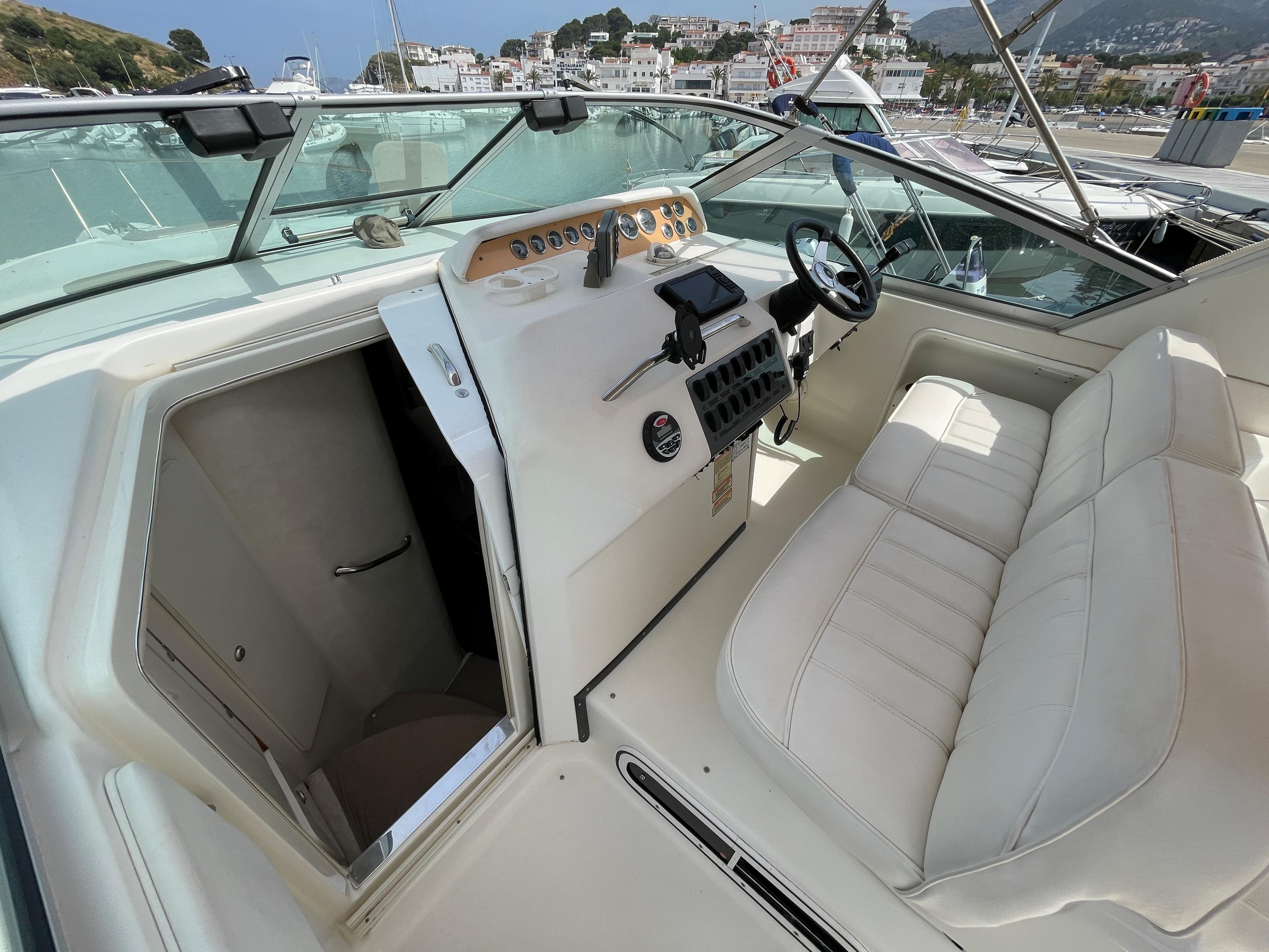 The image shows the cockpit of a 1997 Sea Ray 290 Sundancer with beige leather seats and a helm station.