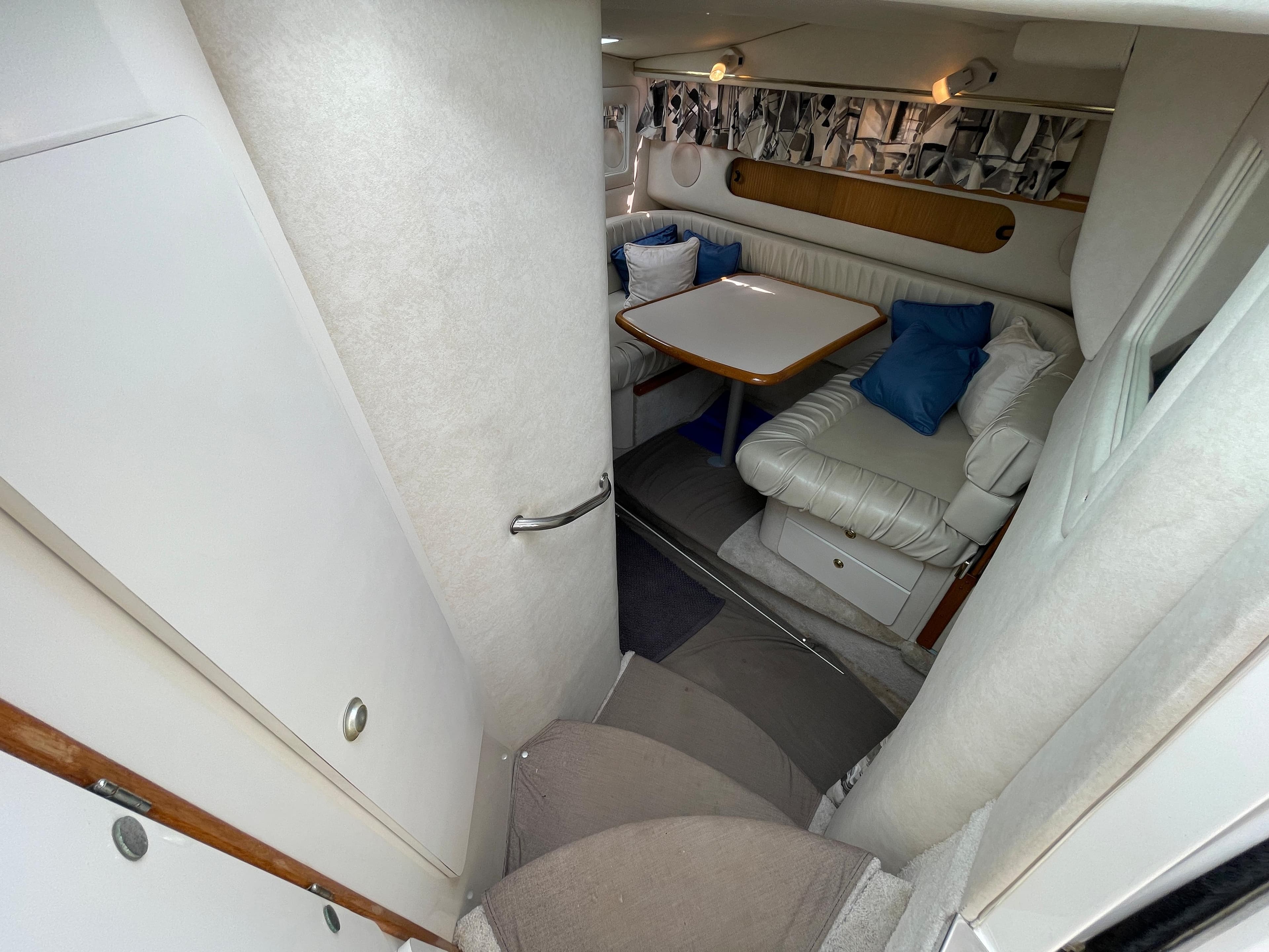 Interior view of a 1997 Sea Ray 290 Sundancer with a cozy seating area and table.