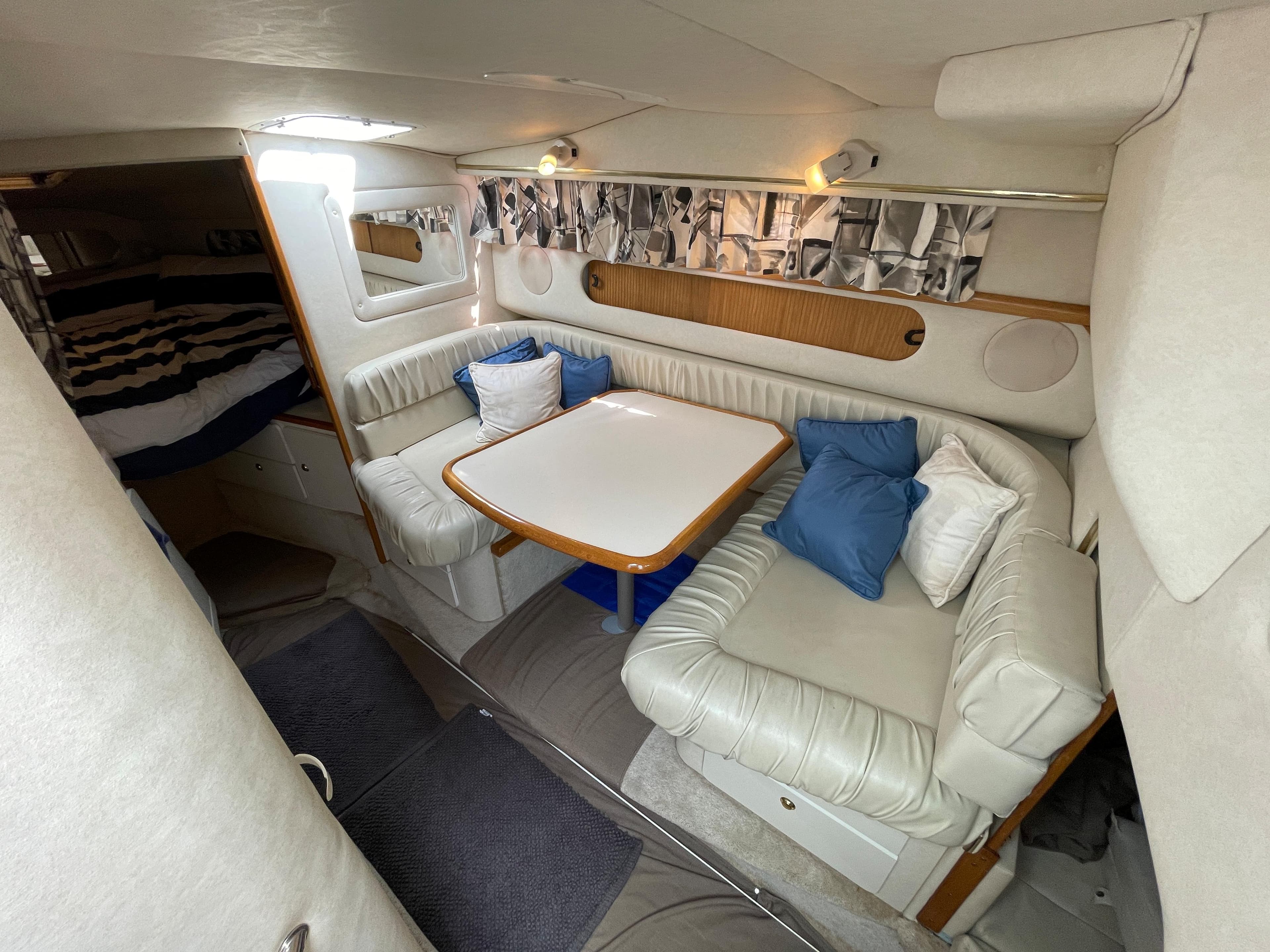 The interior of a 1997 Sea Ray 290 Sundancer features a cozy seating area with a table and cushions.