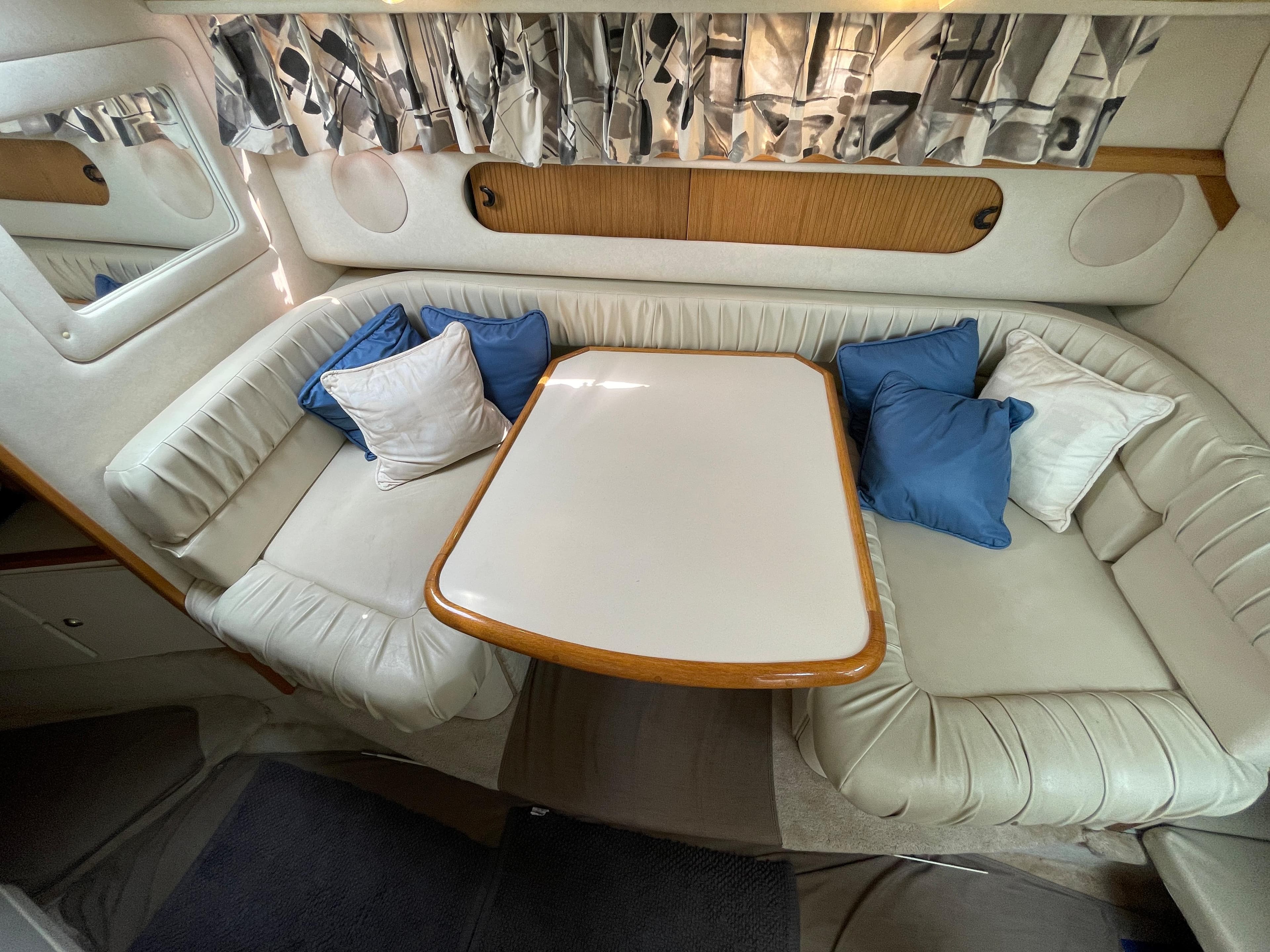 Interior of a 1997 Sea Ray 290 Sundancer with cushioned seating and a table.
