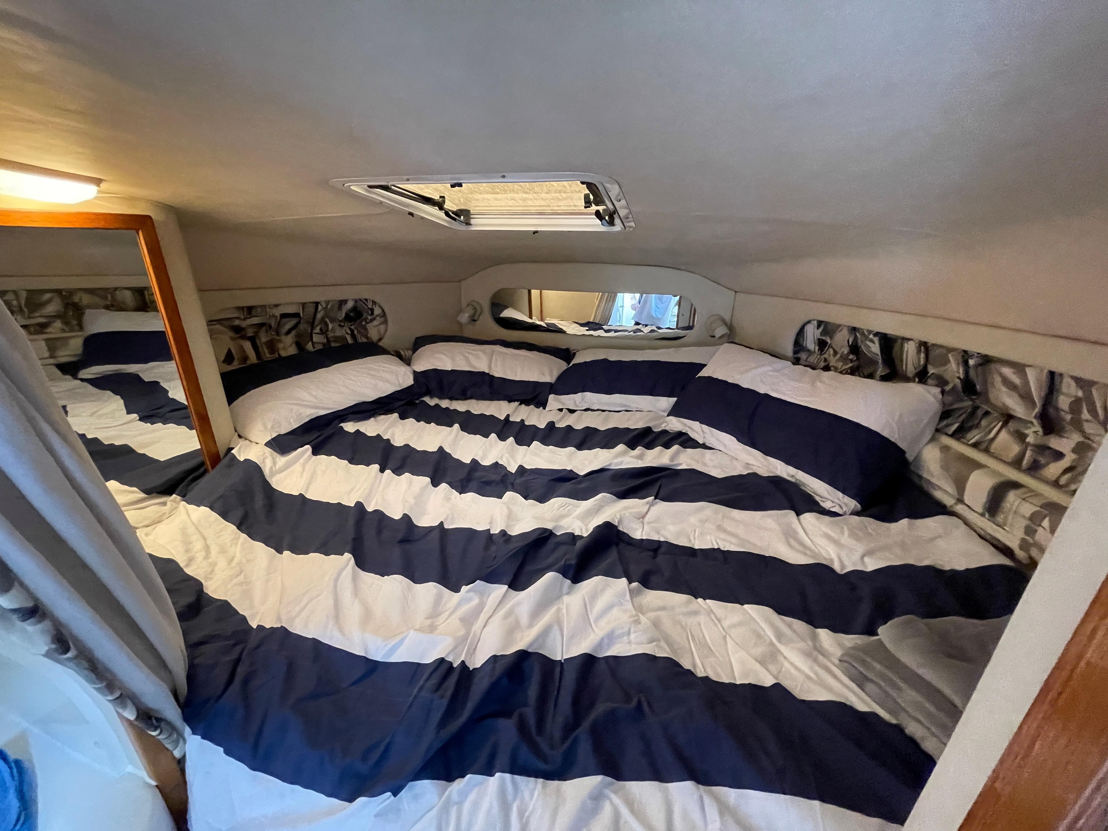 The cabin of a 1997 Sea Ray 290 Sundancer with striped bedding.