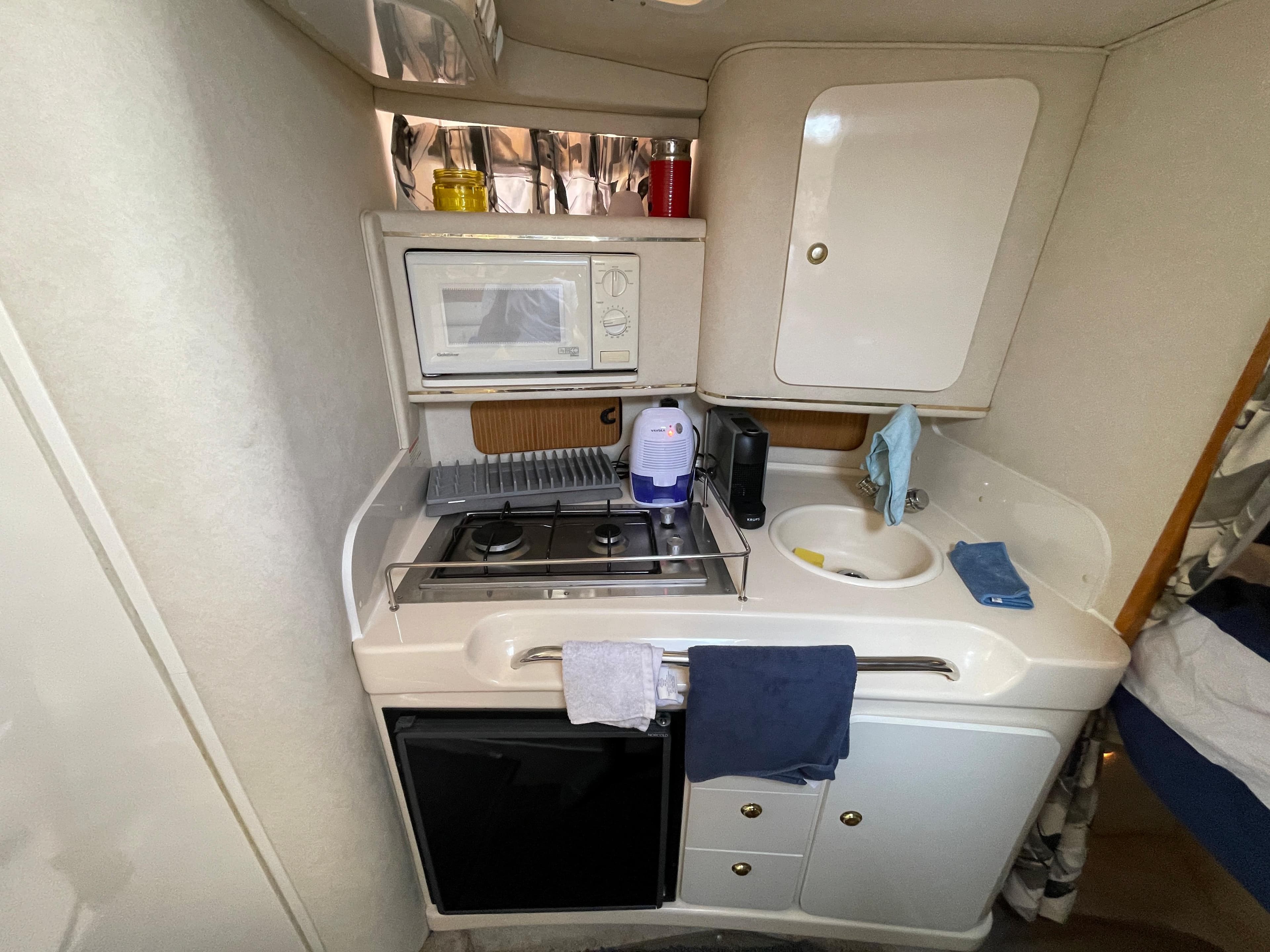 Compact kitchen in a 1997 Sea Ray 290 Sundancer with stove, microwave, and sink.