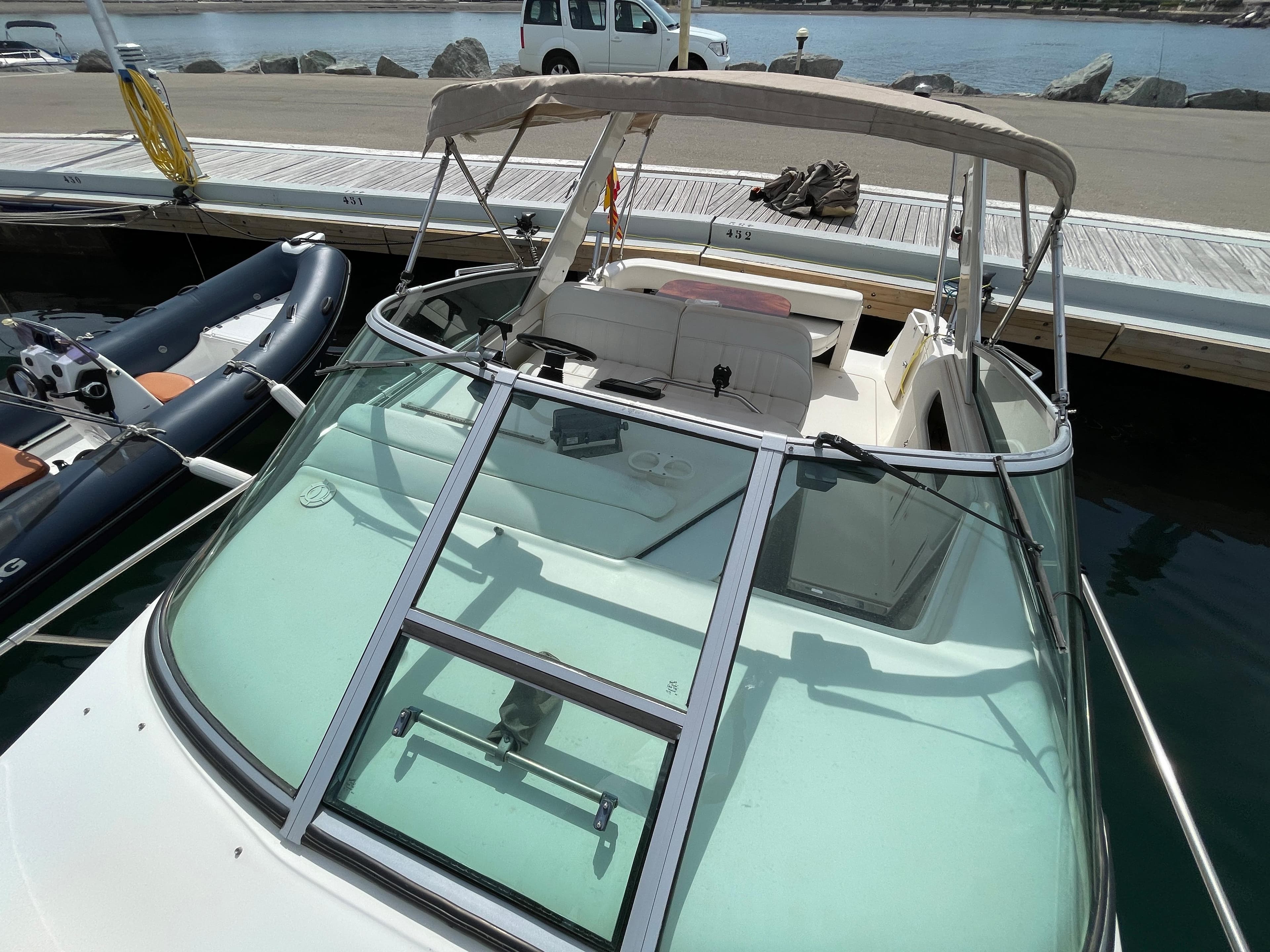 A 1997 Sea Ray 290 Sundancer docked. It features a beige canopy and clear windows.
