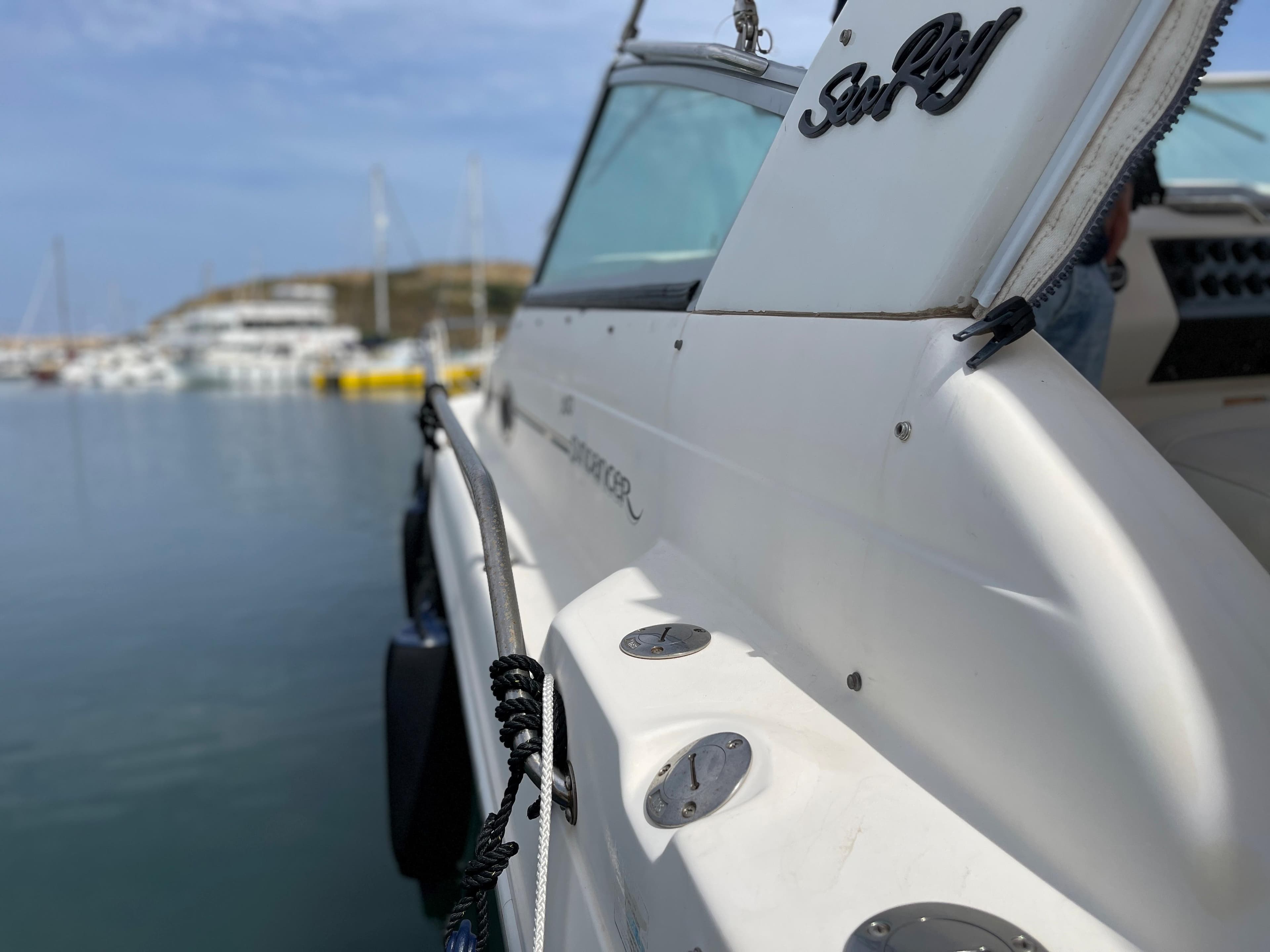 A 1997 Sea Ray 290 Sundancer is docked, with a calm harbor in the background.