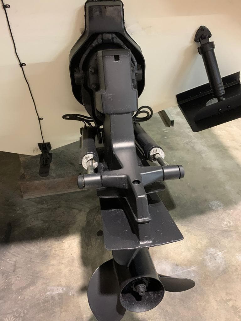 Close-up of a boat propeller and drive assembly on a concrete floor.