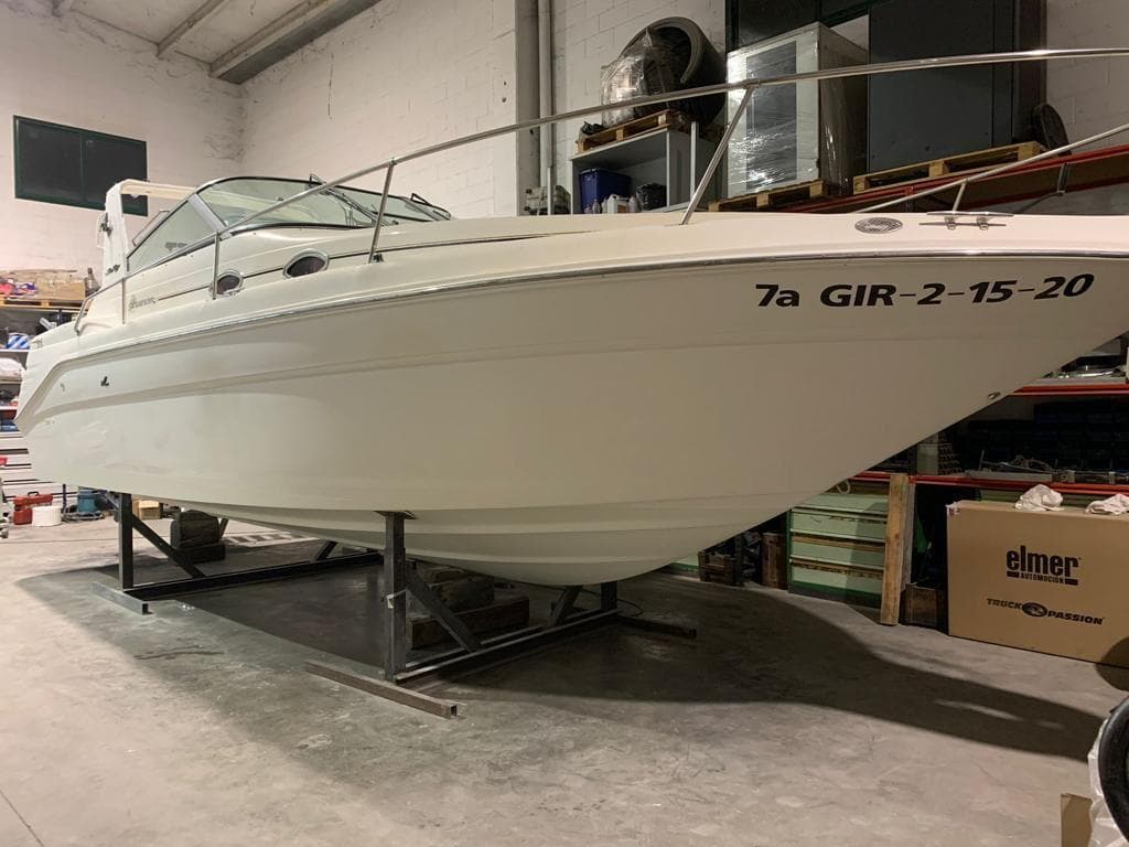 A 1997 Sea Ray 290 Sundancer is on a stand in a warehouse.