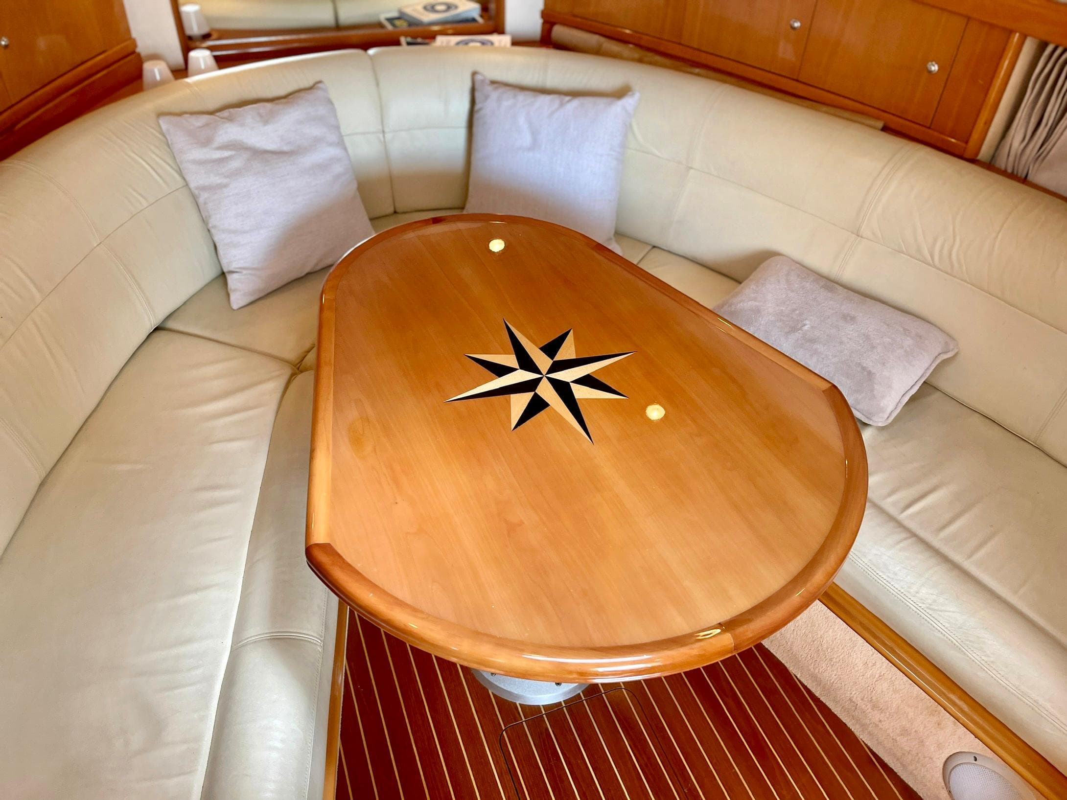 Interior of 2003 Windy Bora 40 yacht with elegant wooden table and cushioned seating.