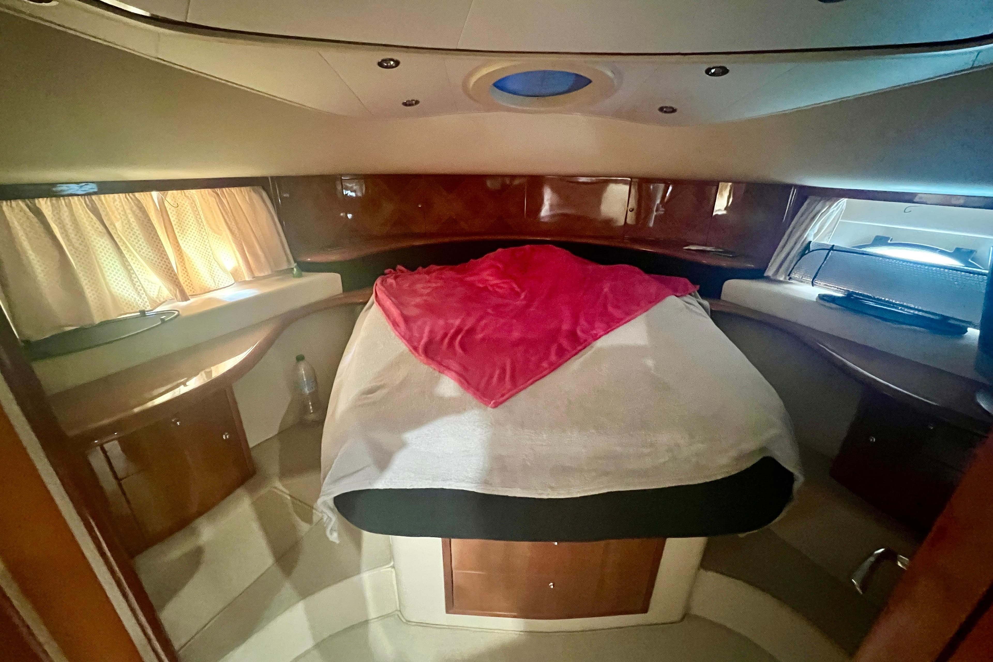 Luxurious cabin interior of 2002 Aicon 56 yacht with cozy bed and elegant wood finish.