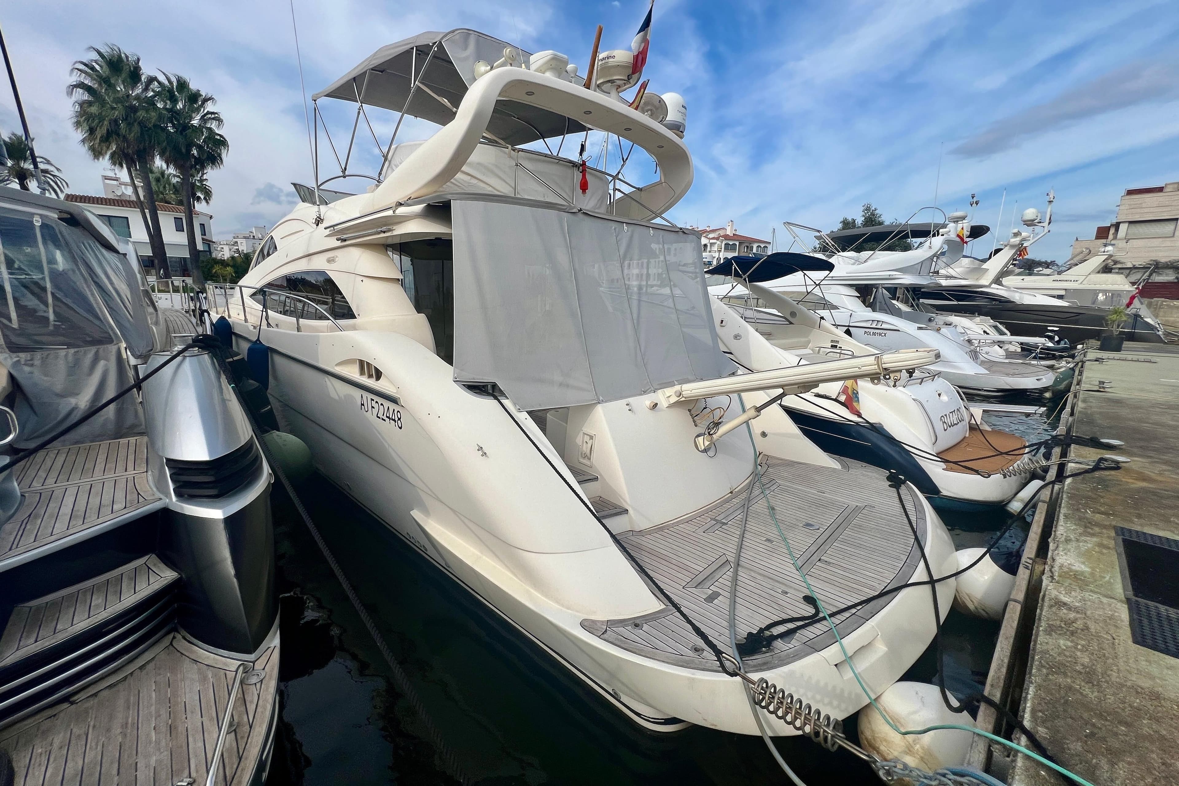 Aicon 56 yacht from 2002 docked at a marina, surrounded by other boats.