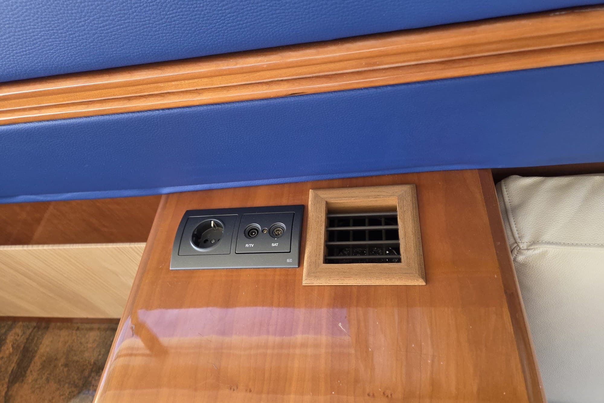 Power outlet and vent on 1994 Azimut 43 yacht's wooden interior panel.