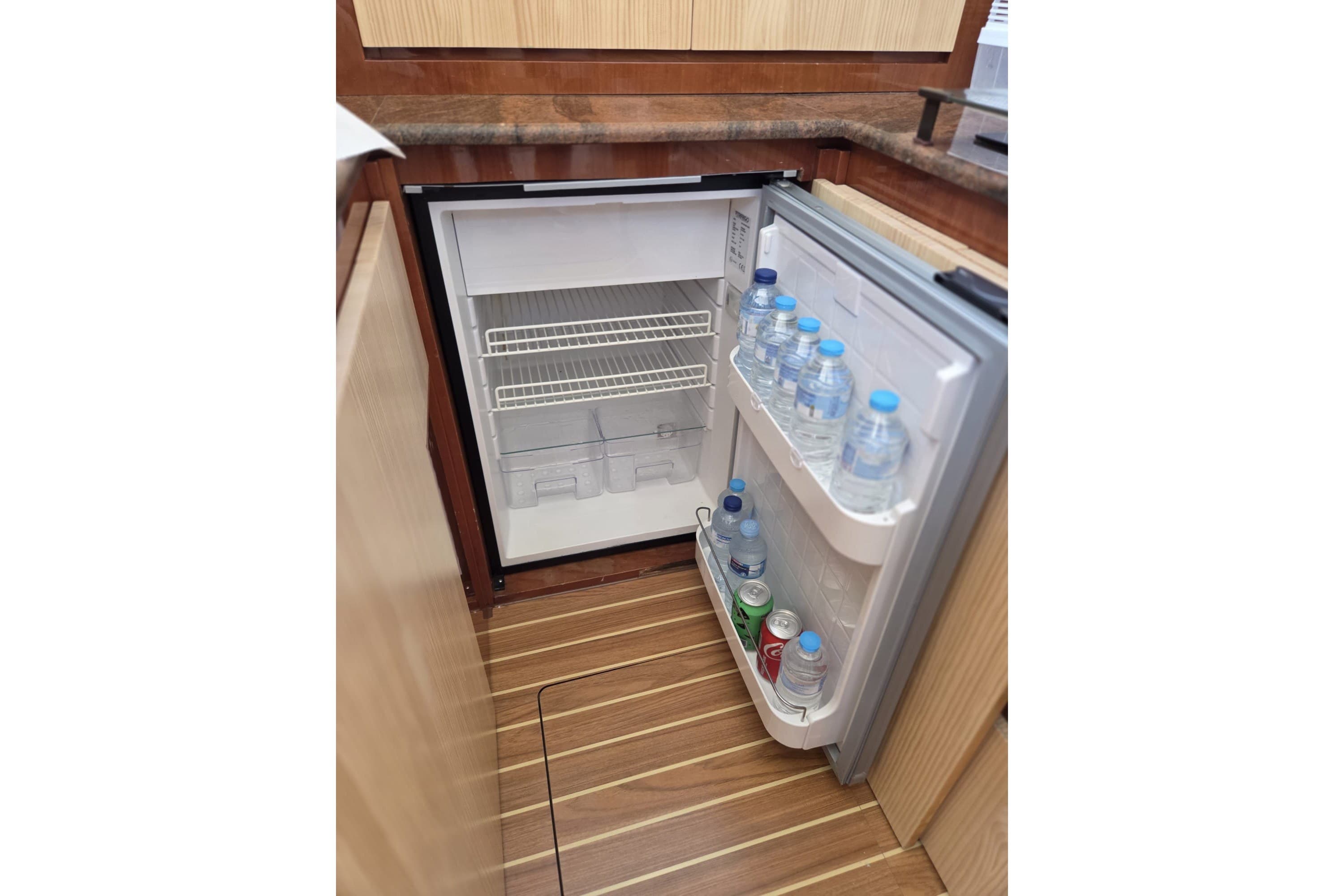 Open fridge on Azimut 43 yacht, stocked with water bottles and soda cans, 1994 model.