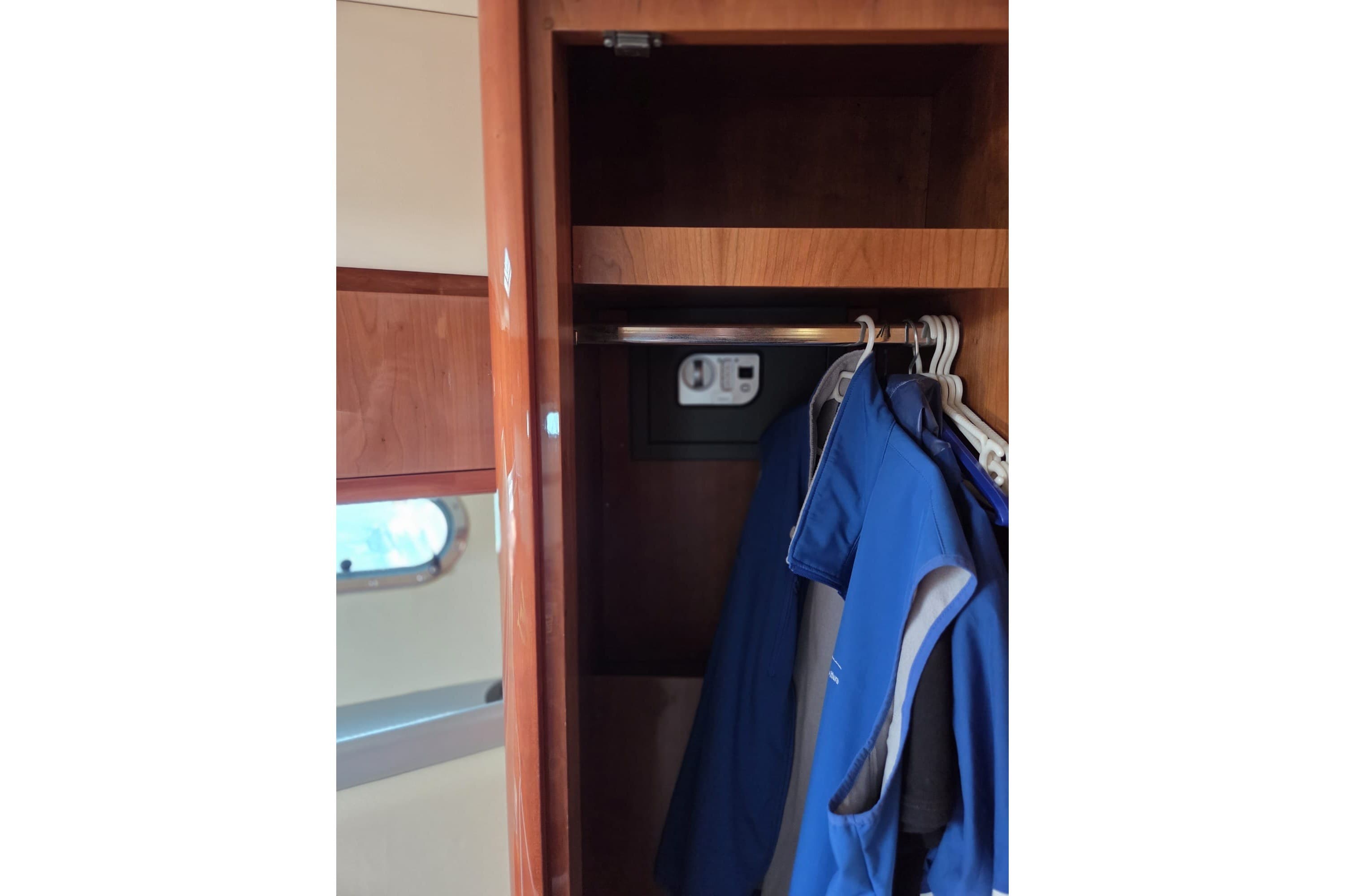 Wooden closet interior with blue jackets on hangers, Azimut 43 yacht, 1994 model.