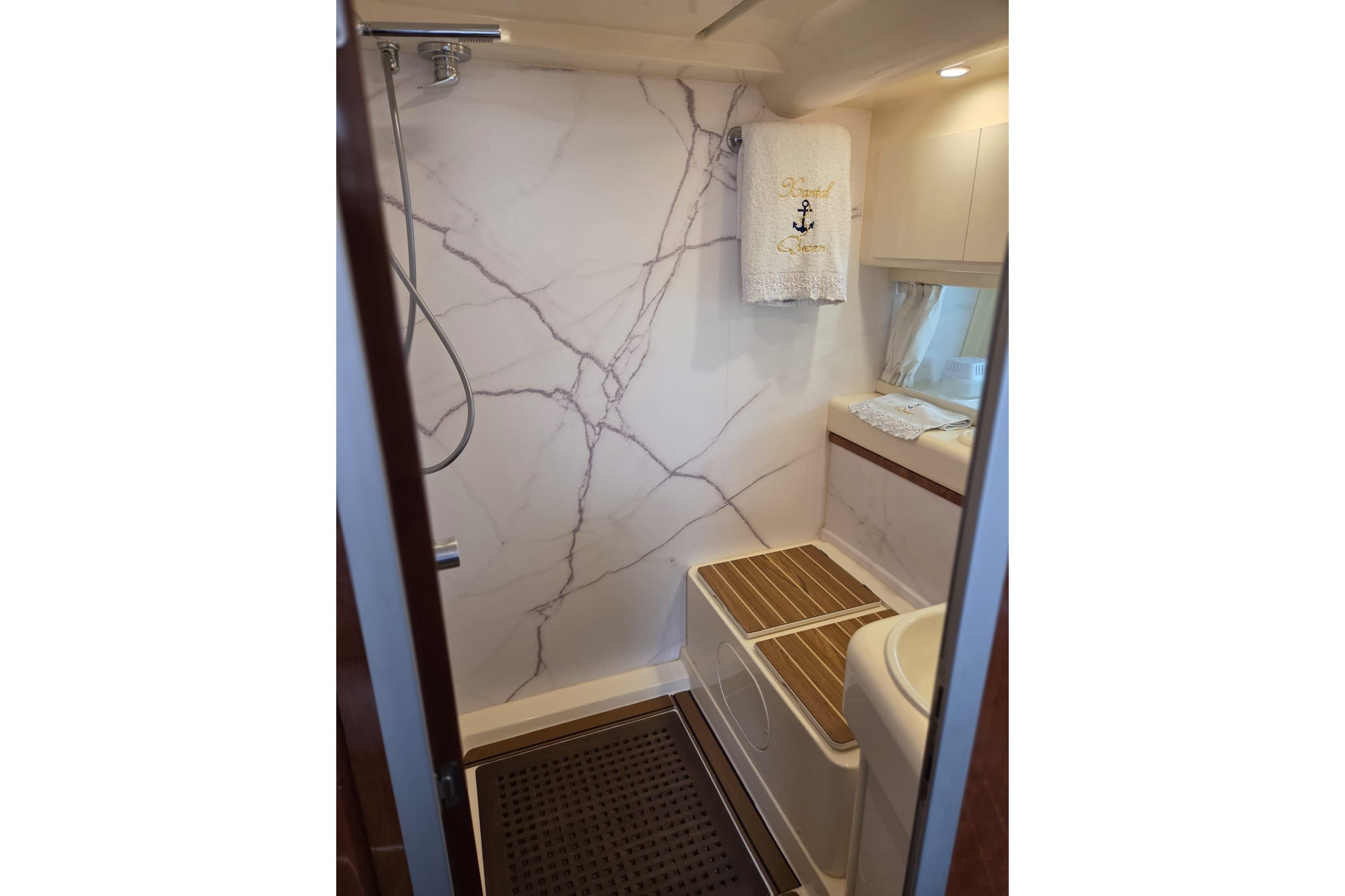 Luxurious bathroom in a 1994 Azimut 43 yacht with marble walls and elegant fixtures.