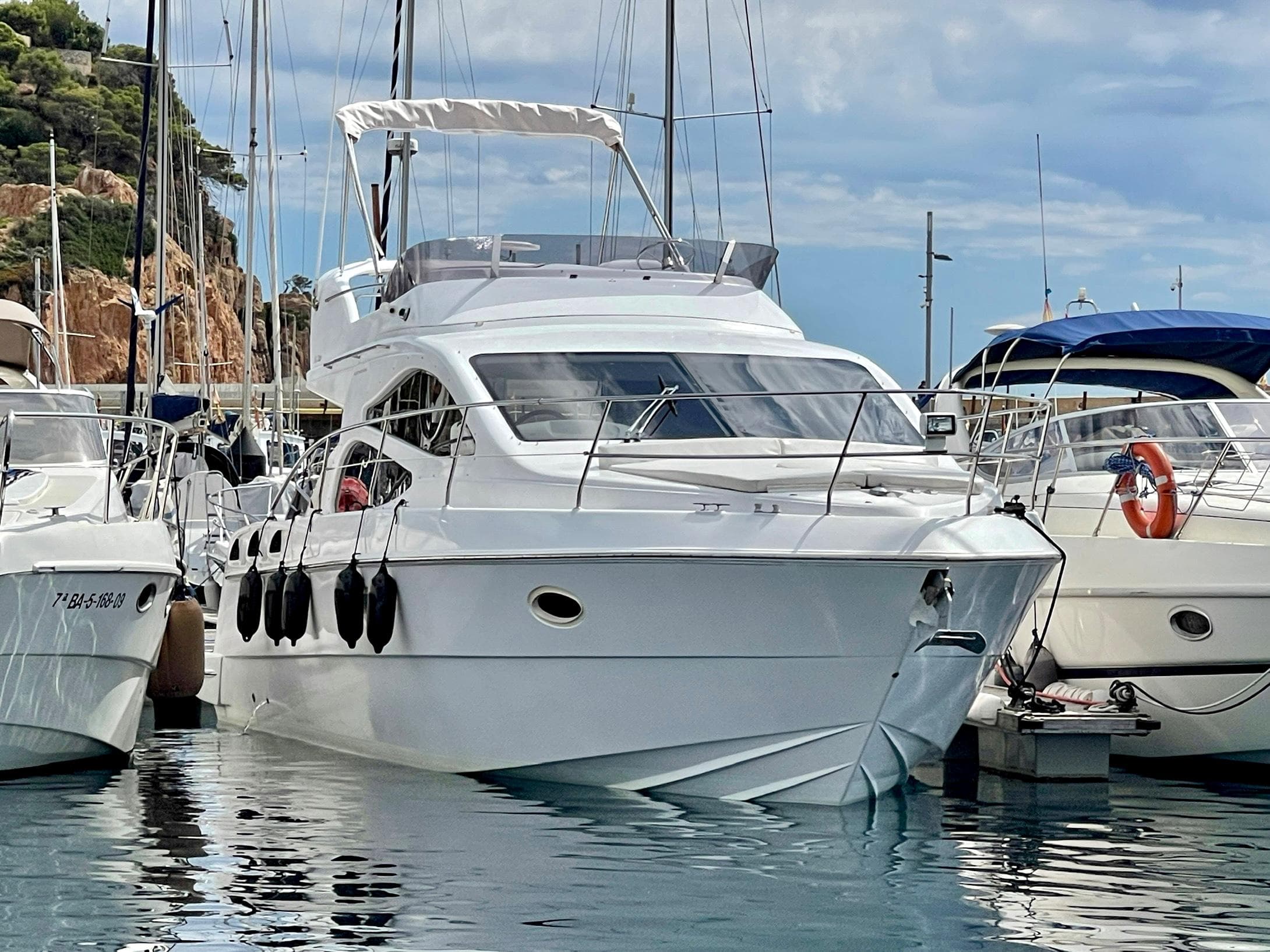 2006 Genesis Boats 37 Flybridge yacht docked in a marina, surrounded by other boats.