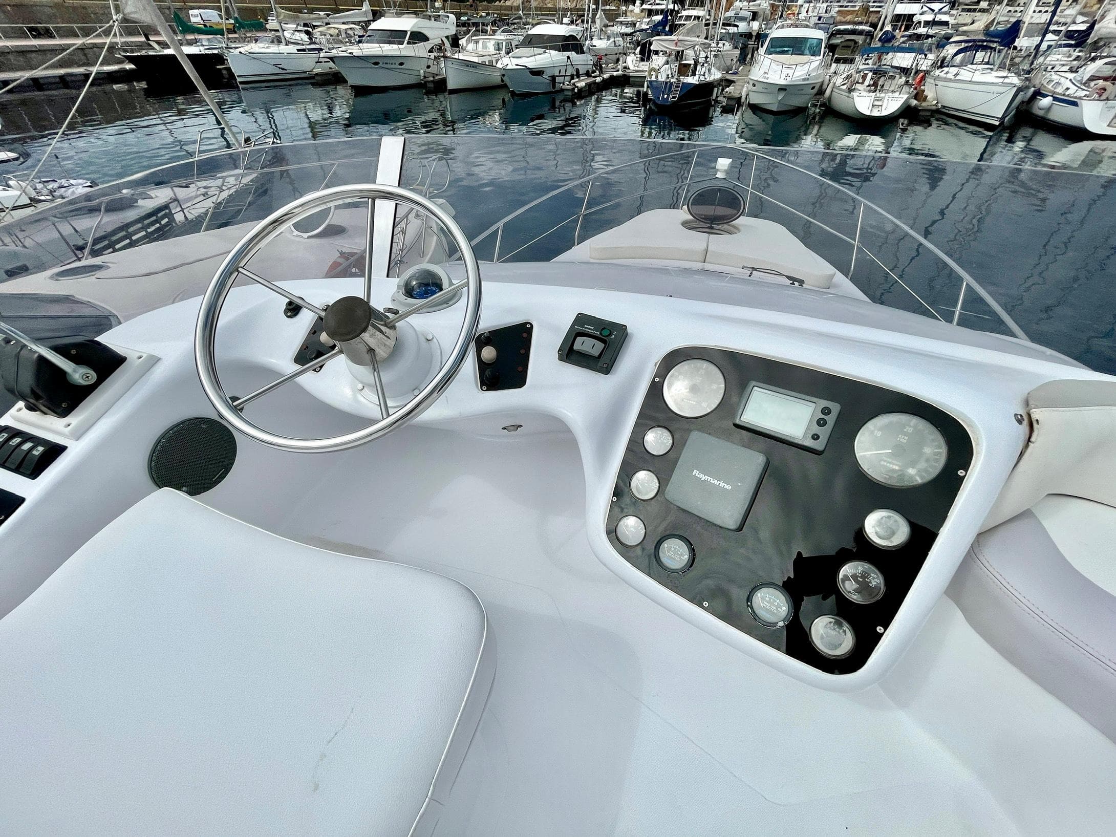 Helm of 2006 Genesis Boats 37 Flybridge with steering wheel and control panel, docked at marina.