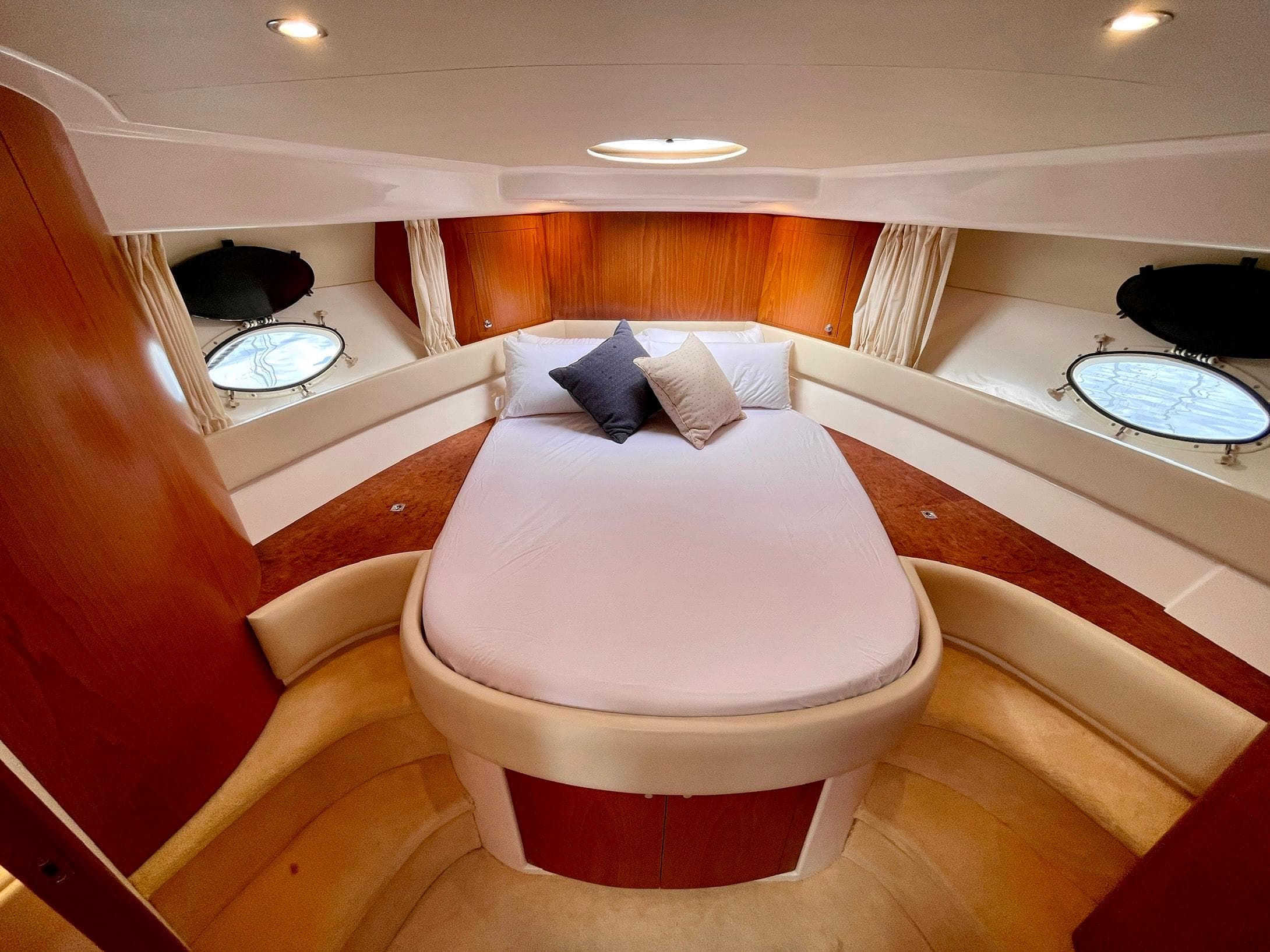 Luxurious cabin interior of 2006 Genesis Boats 37 Flybridge with cozy bed and porthole windows.
