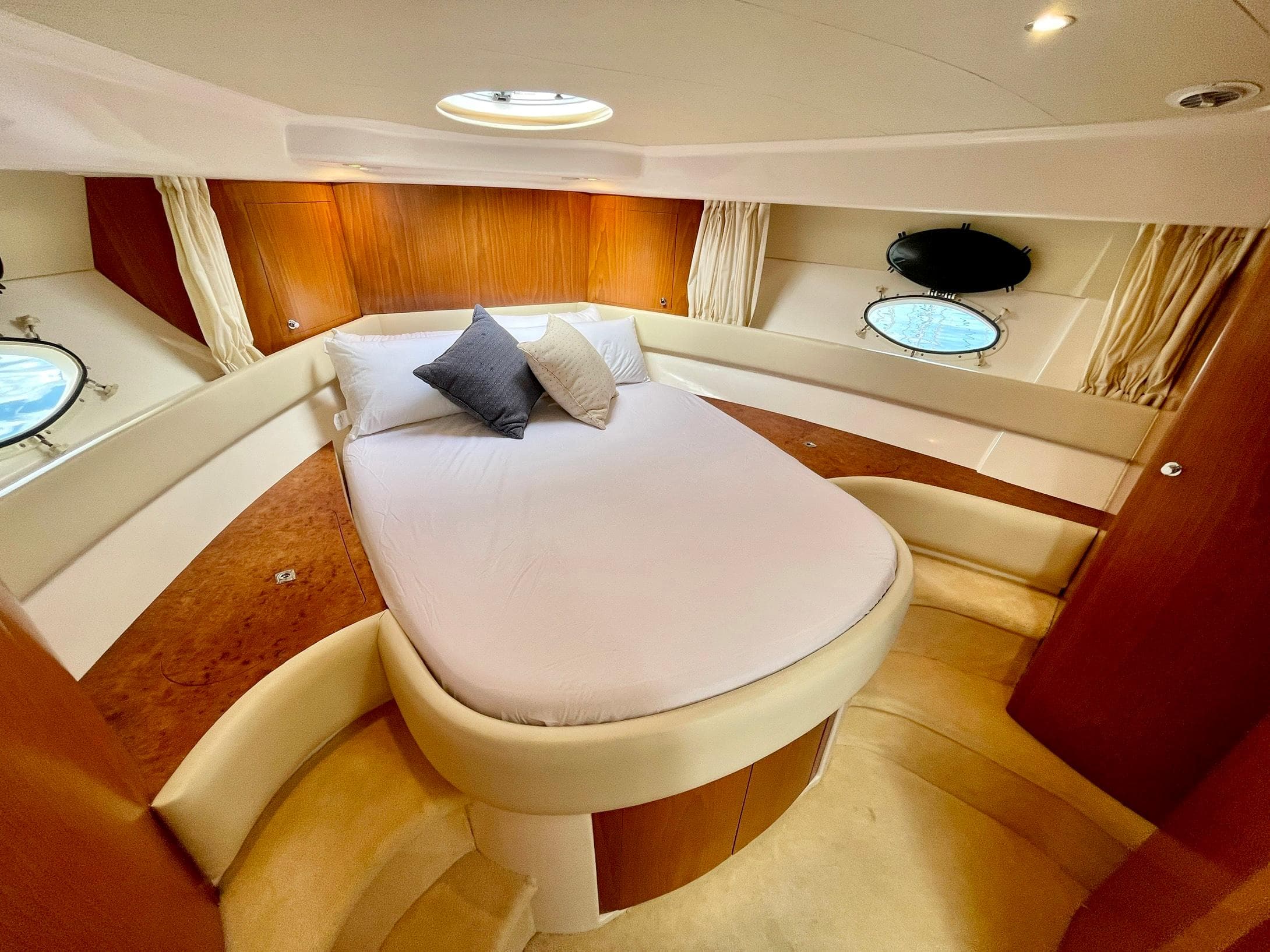 Luxurious cabin interior of 2006 Genesis Boats 37 Flybridge with cozy bed and porthole windows.