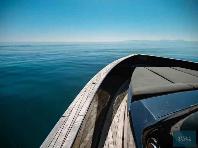 Teak bow of a boat facing a calm sea